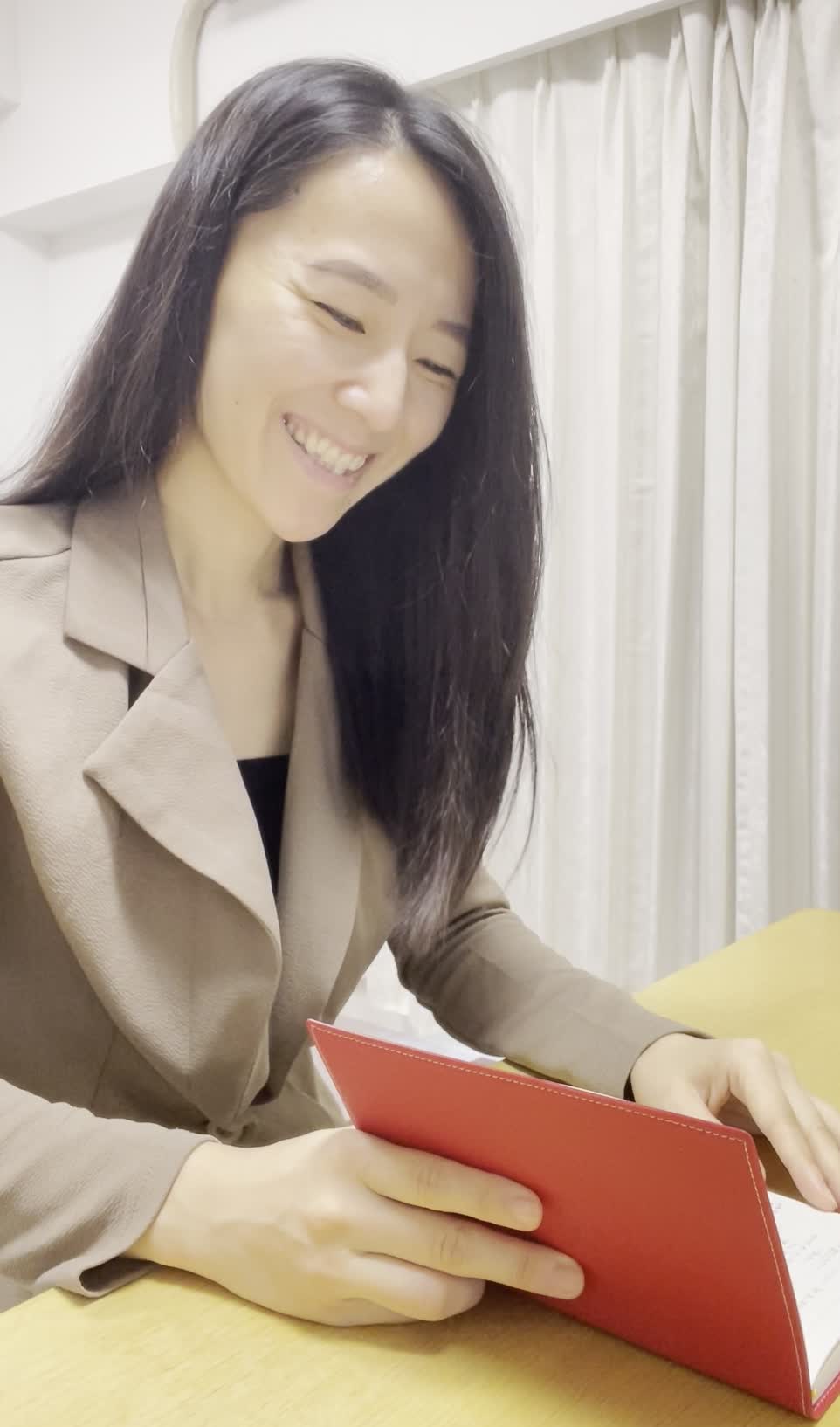 テーブルに置いた手帳を眺め、「これで生活が安定する」と微笑む表情