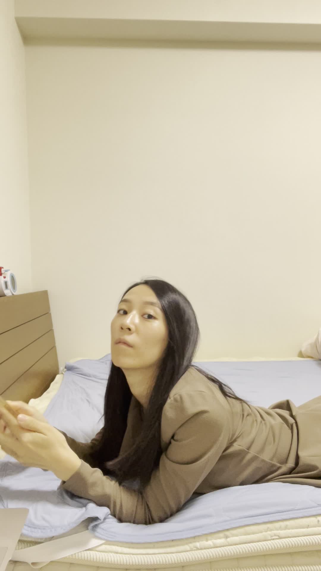 ベッドで横になり、スマホで「債務整理の口コミ」をチェックする集中した様子