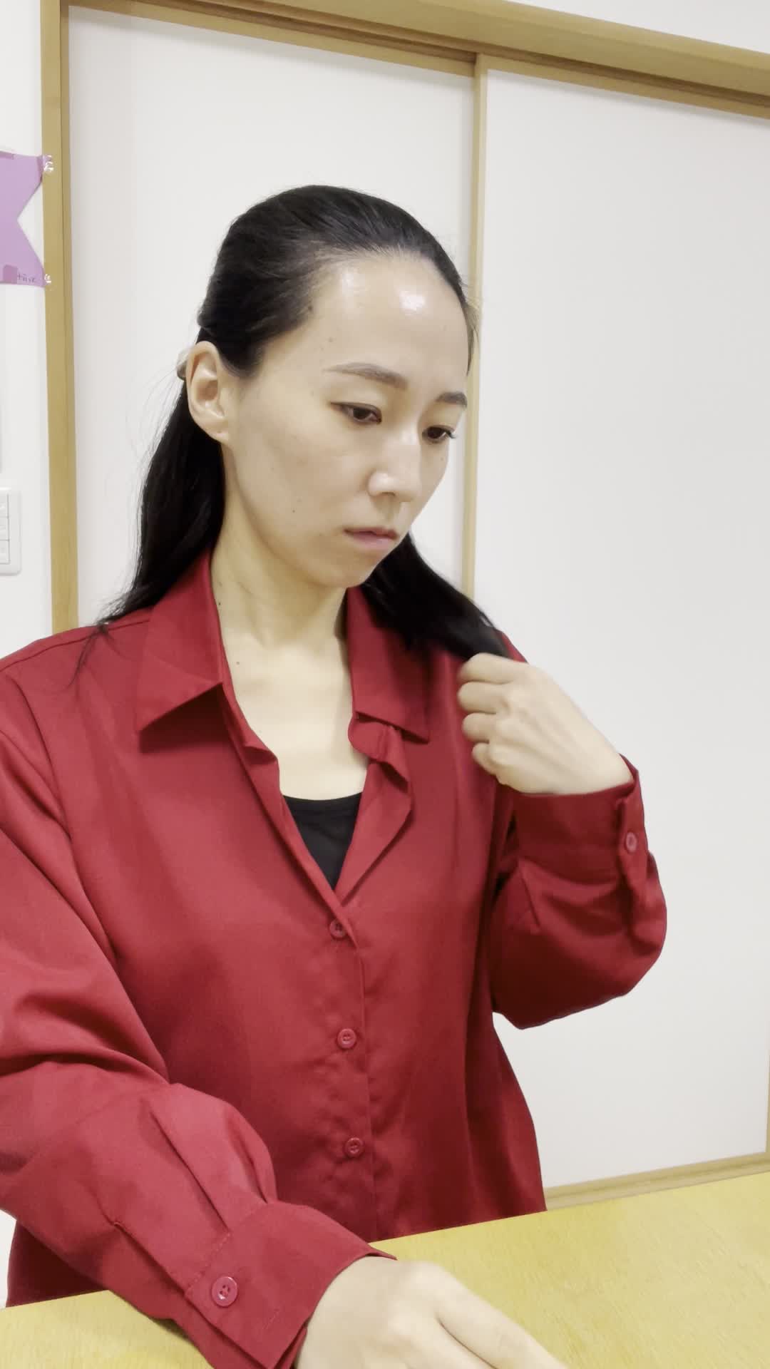 椅子に座り、仕事中に髪のパサつきが気になり、少しイライラする表情を見せる姿