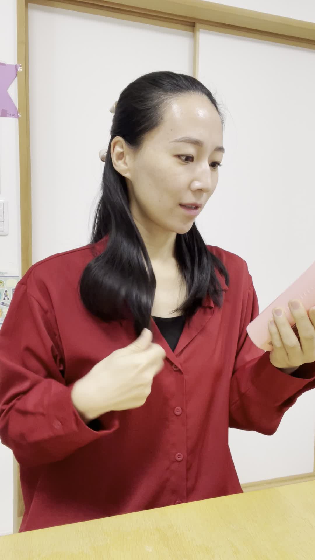 椅子に浅く腰掛け、髪を手ぐしで整えながら「このシャンプー試してみよう」と決意する表情