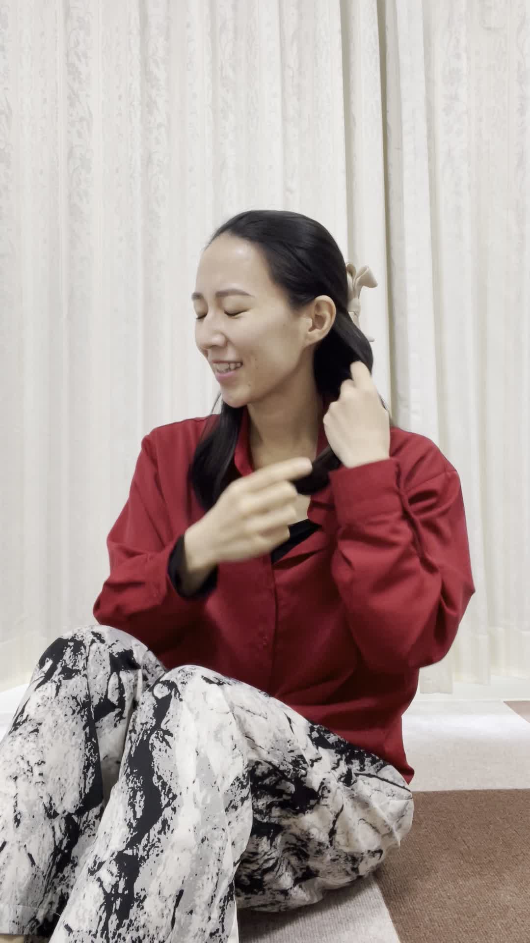 床で膝を立てて座り、「髪がまとまらなくて朝から大変」と困った様子を見せる仕草