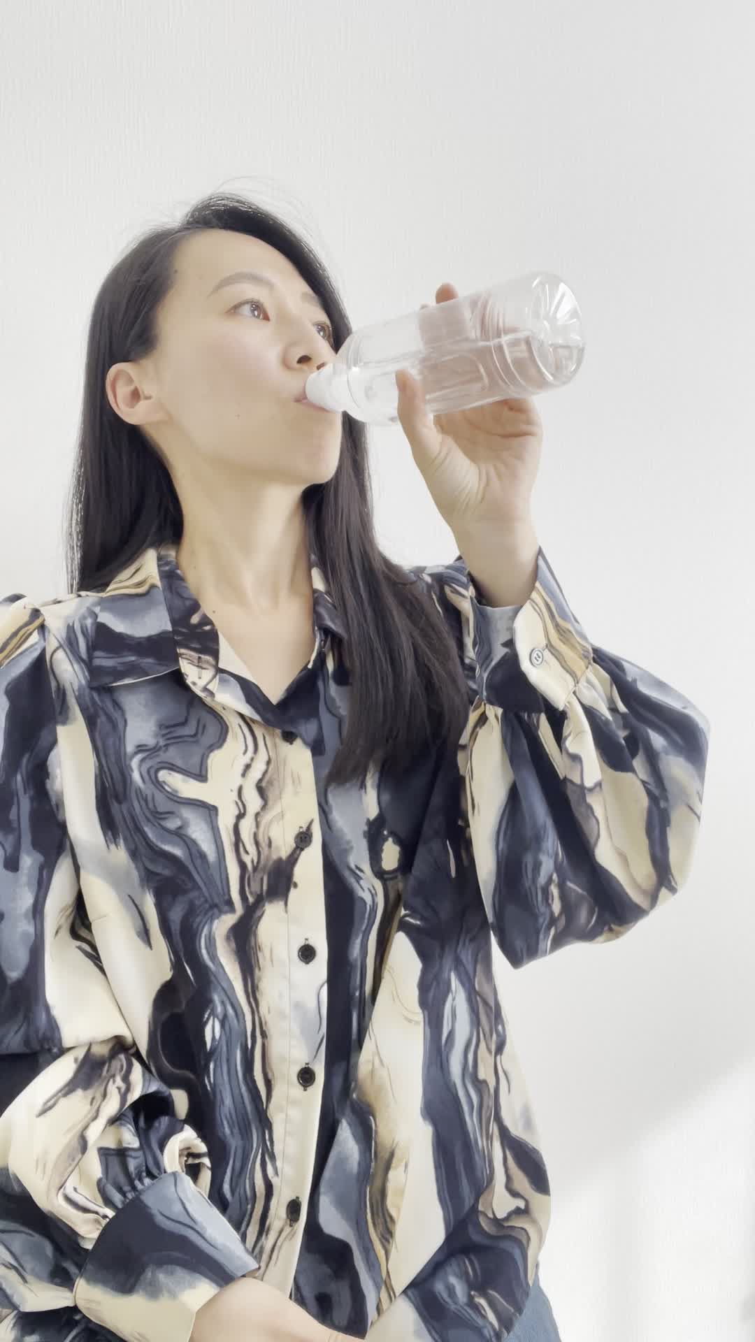椅子に座り、ペットボトルの水を飲みながら「もっと手軽に冷たい水が飲めたらいいのに」と考える表情