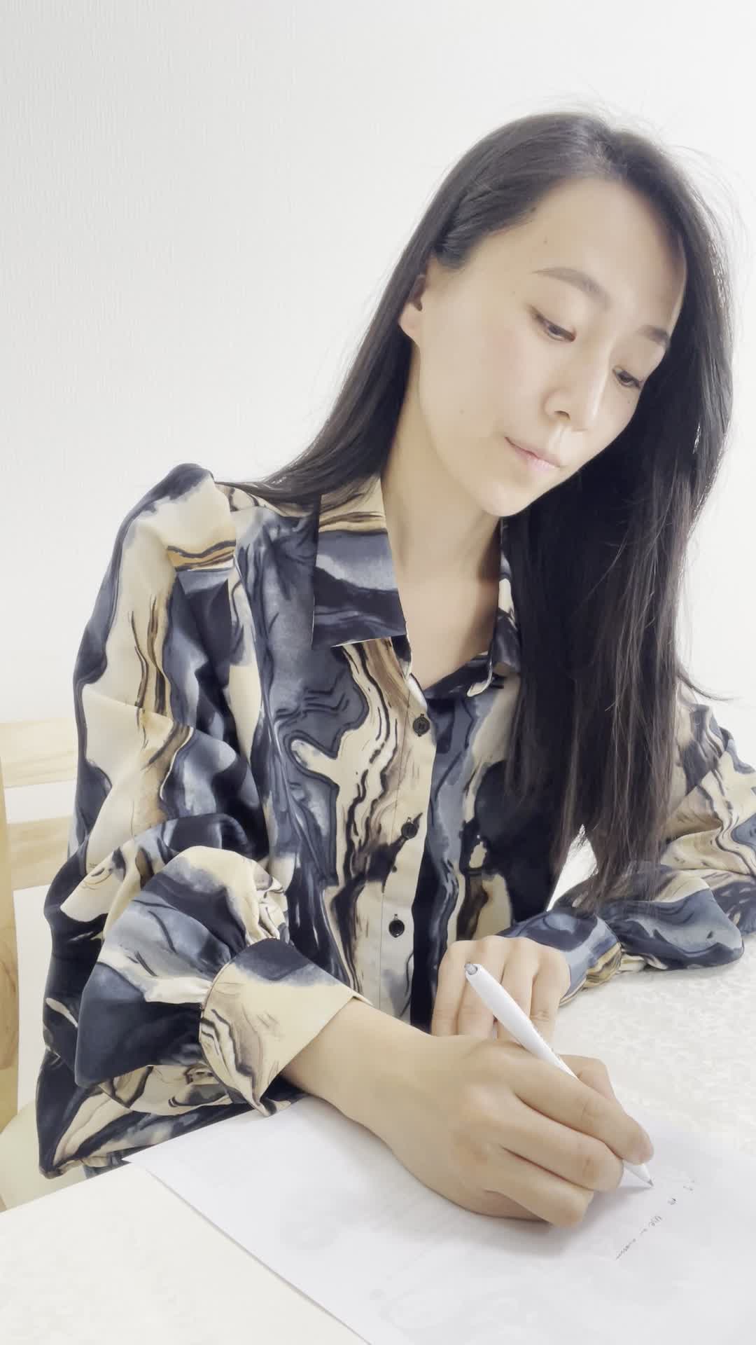 椅子に腰掛け、紙にウォーターサーバーのメリットを書き出している様子