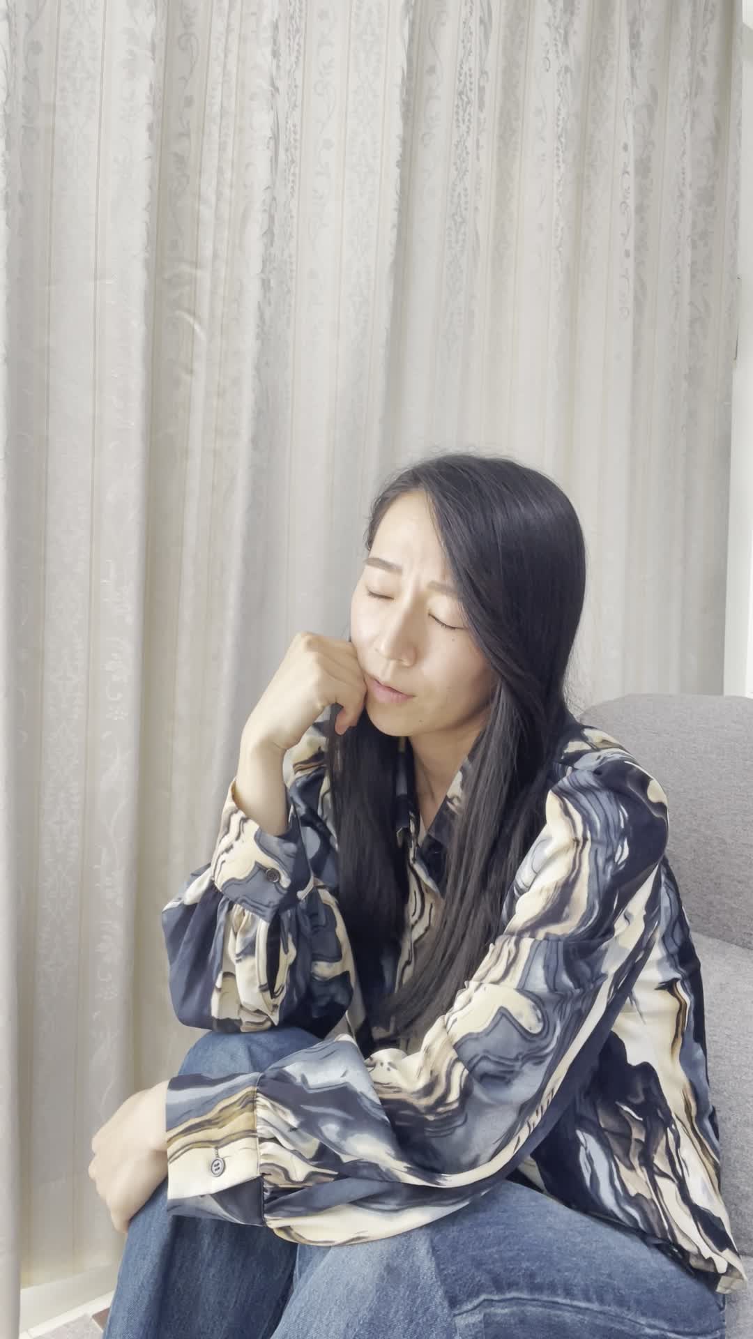 ソファで膝を抱え、熱いお茶を飲みたいけど準備が面倒そうな顔をして悩む様子