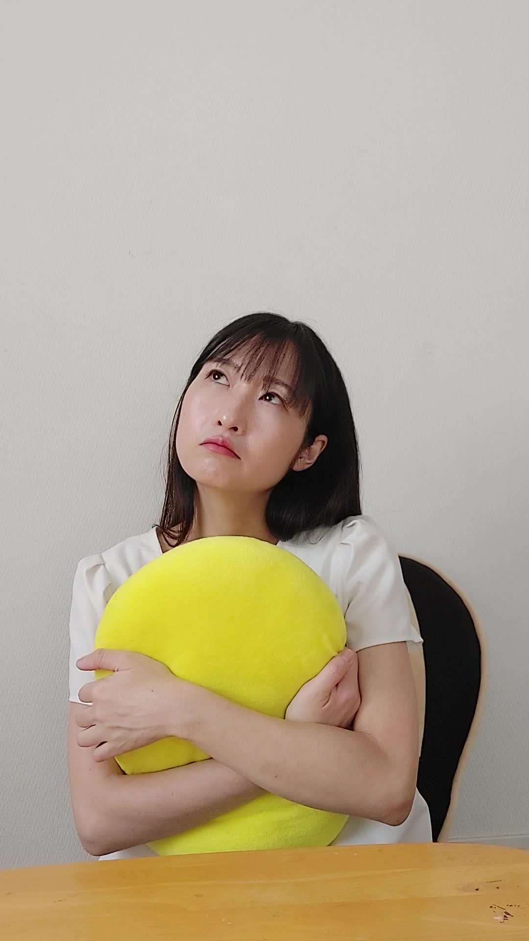 ソファでクッションを抱え、「これで匂いが改善するかな？」と悩む真剣な表情