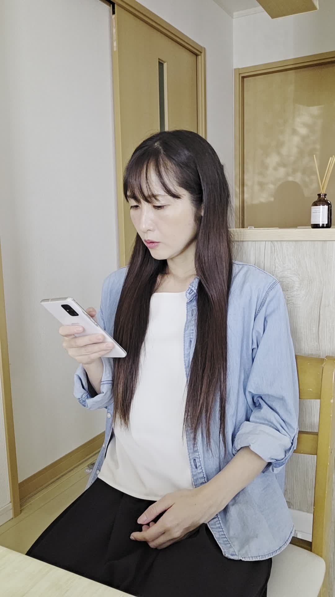 椅子に腰掛け、「腸の調子を整えるための対策を必死に調べる」動作