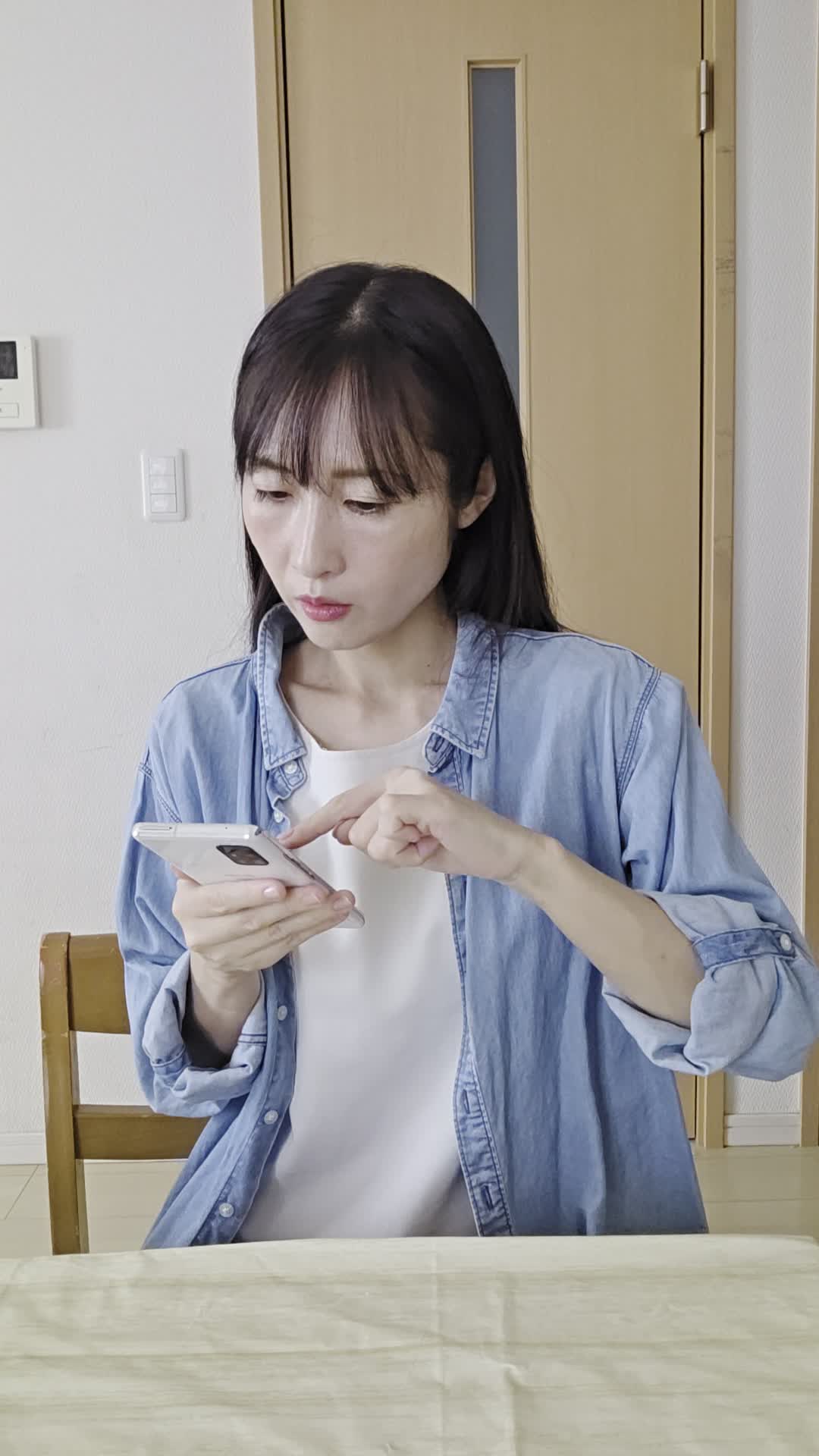 テーブルでスマホを見ながら、「便秘の原因を検索して悩む」真剣な表情