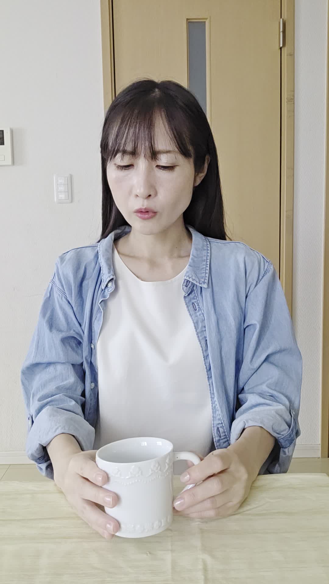 テーブルで飲み物を前に、「これが腸に良いのかな？」と少し戸惑う様子