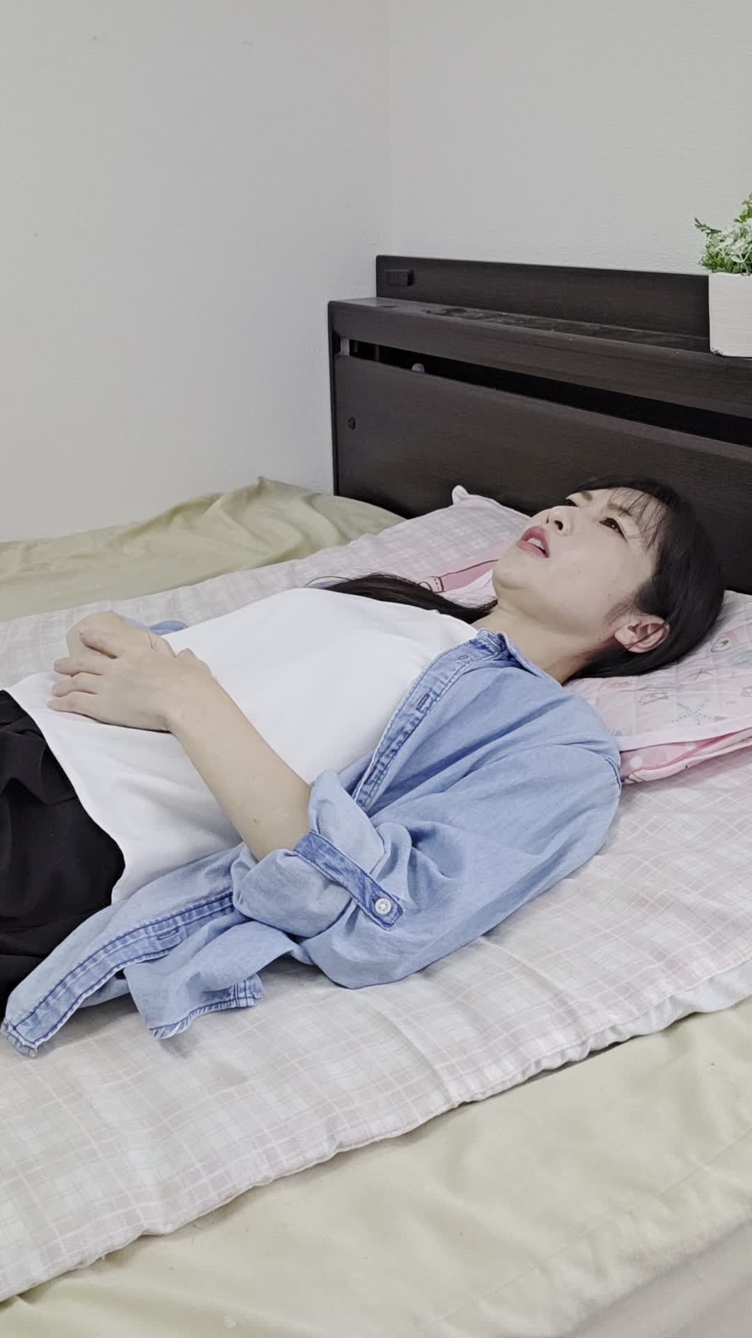 ベッドで横になり、「また便秘が続いている…」と眉をひそめて悩む表情