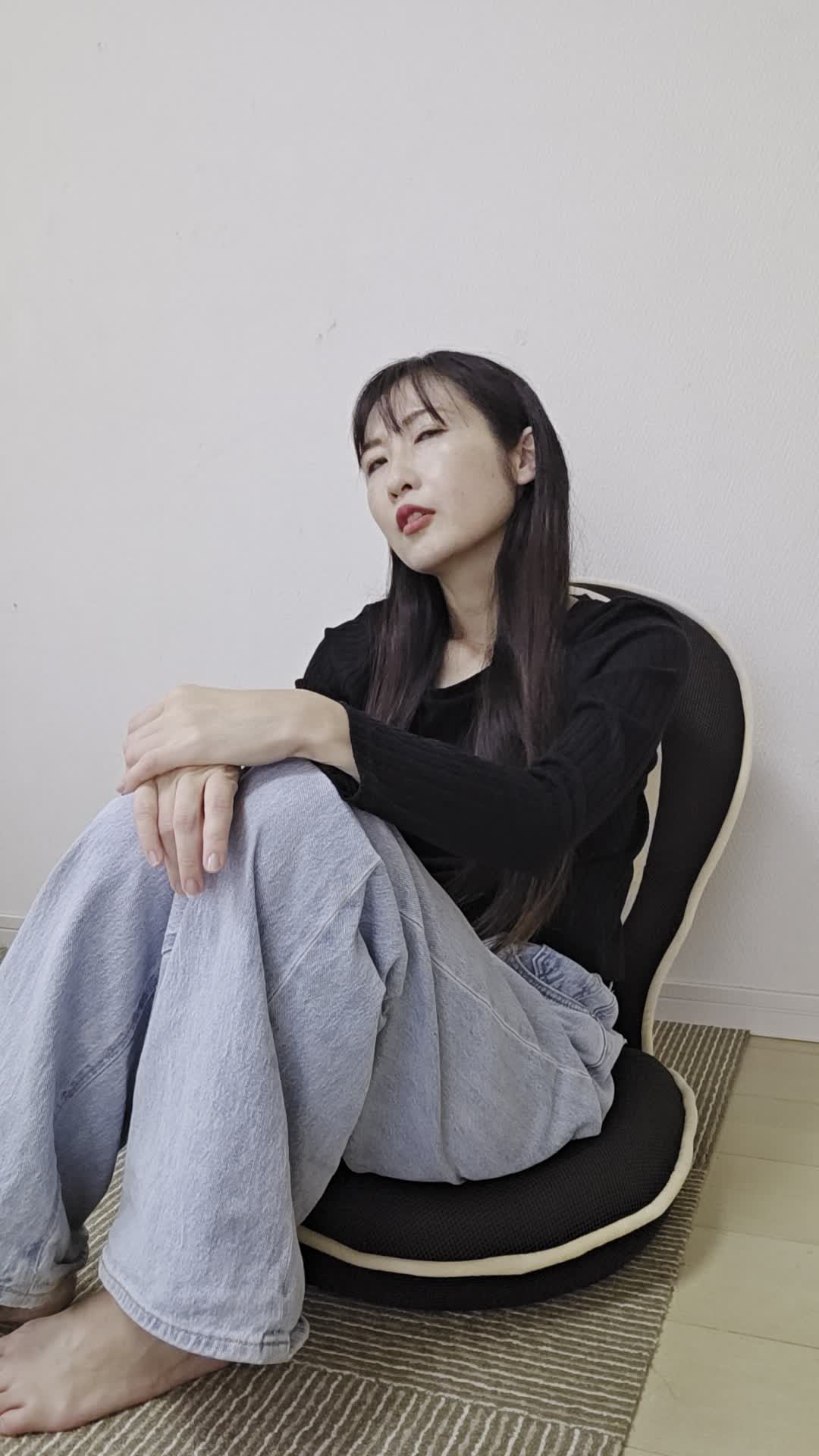 ソファで膝を抱え、「疲れやすくて何もする気が起きない」とため息をつく様子