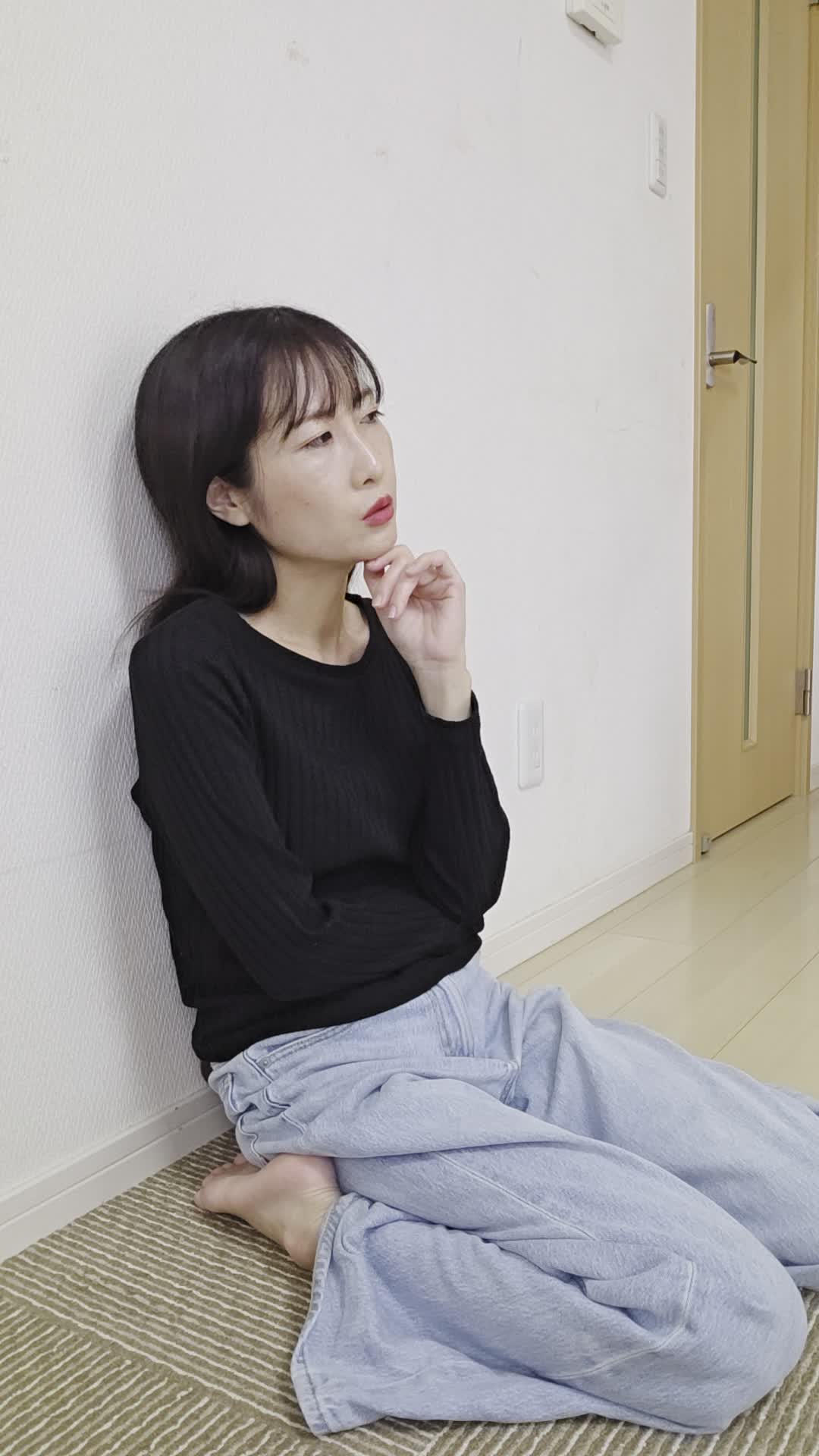 床に膝を崩して座り、「体が重いのは食生活が原因かもしれない」と考え込む姿