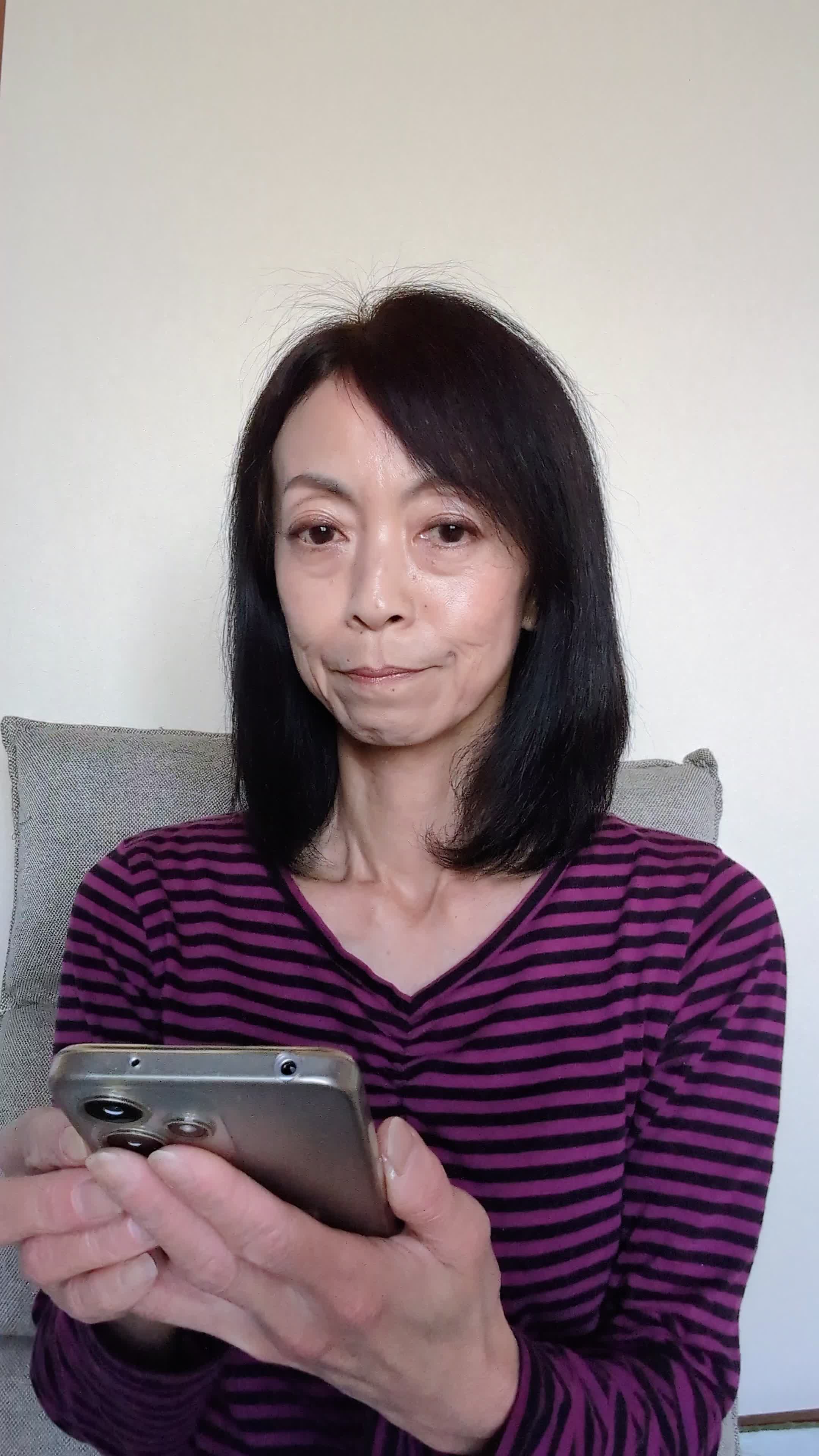 椅子に腰掛け、スマホの画面を見ながら「体臭ケアの口コミを読んで安心する」表情