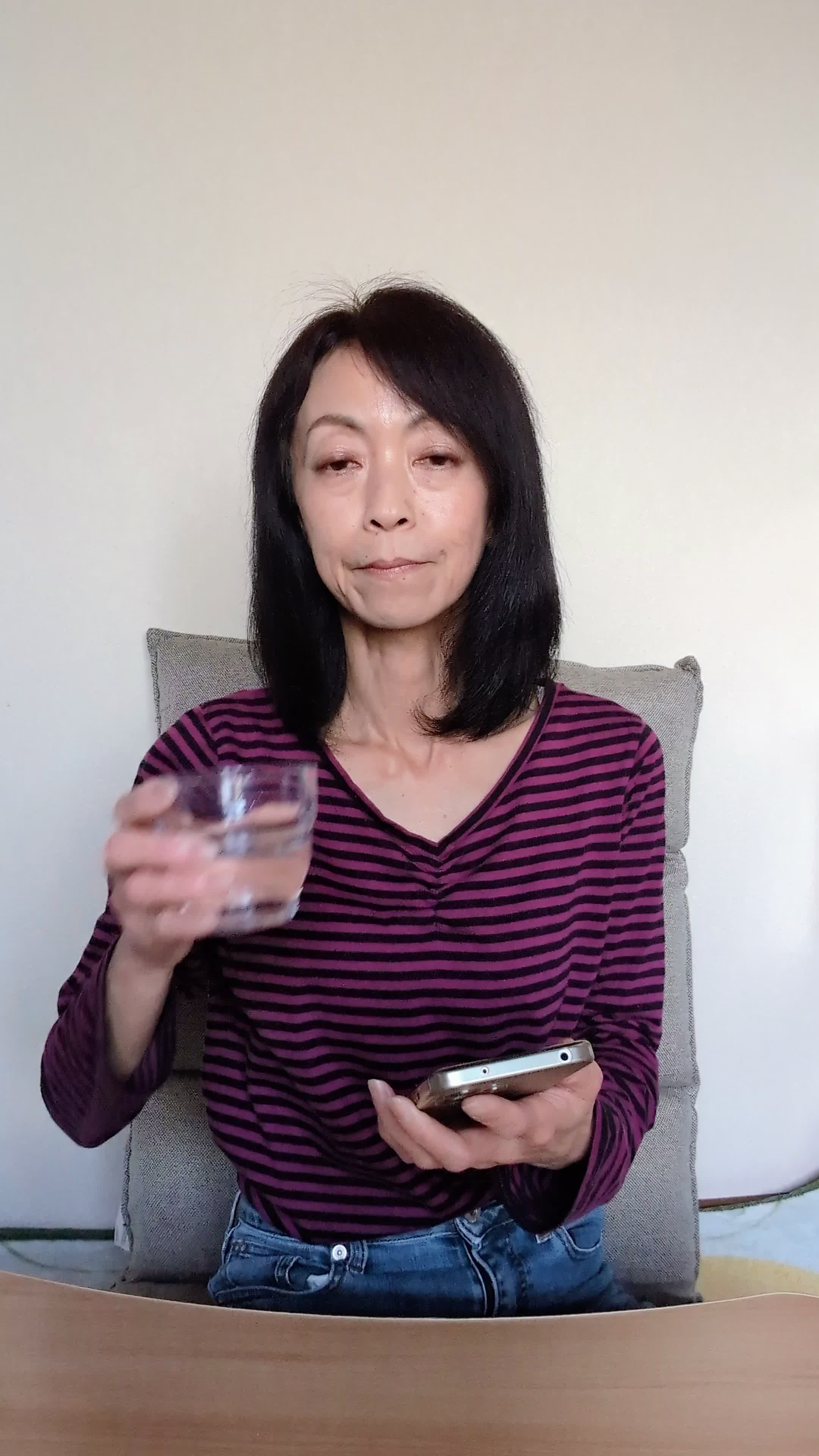 テーブルで水を飲みながら、「次の体臭ケアアイテムを選ぶ」リラックスした表情