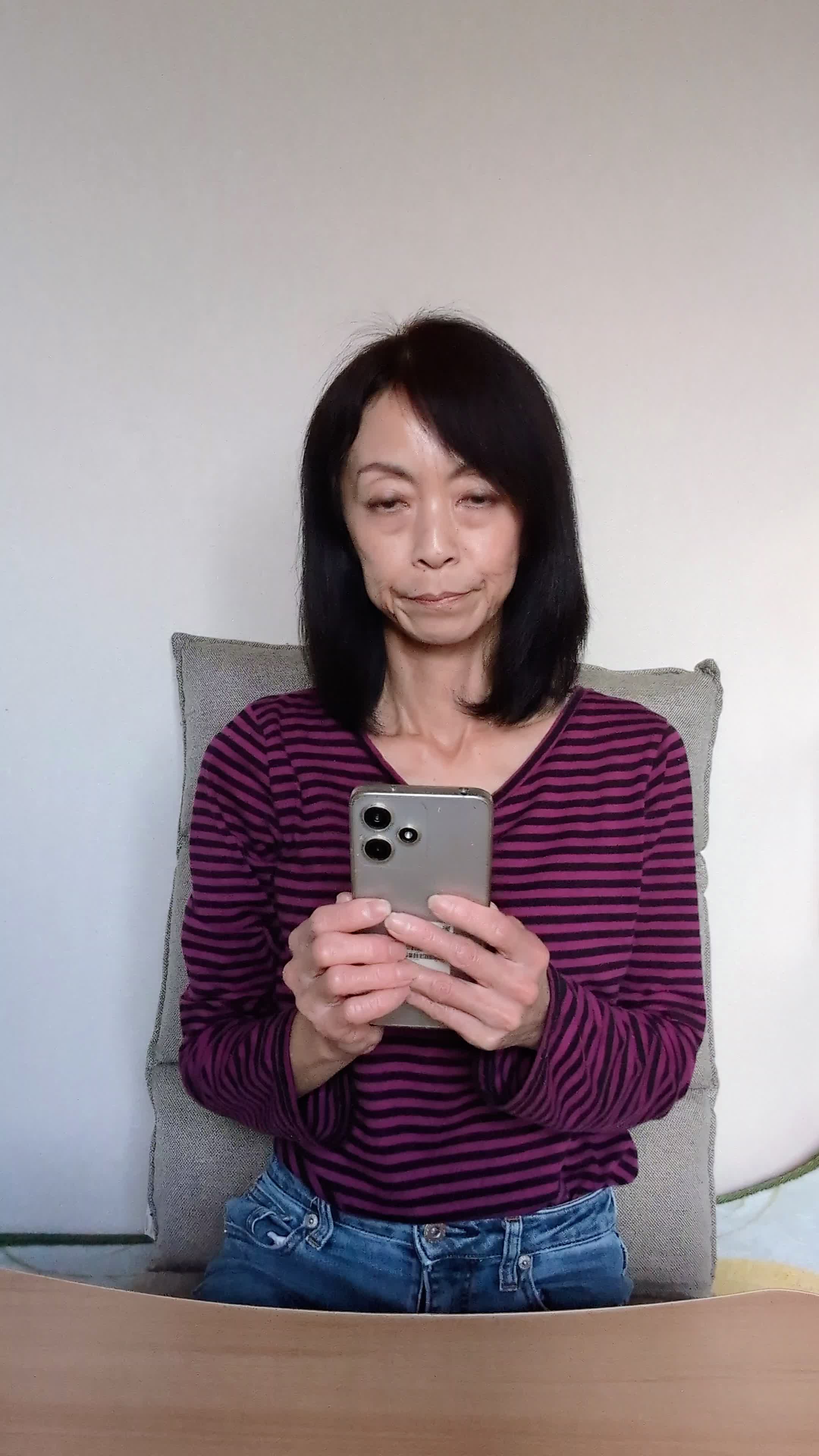 テーブルに置いたスマホを見ながら、「新しいケア方法を試す決意を固める」動作