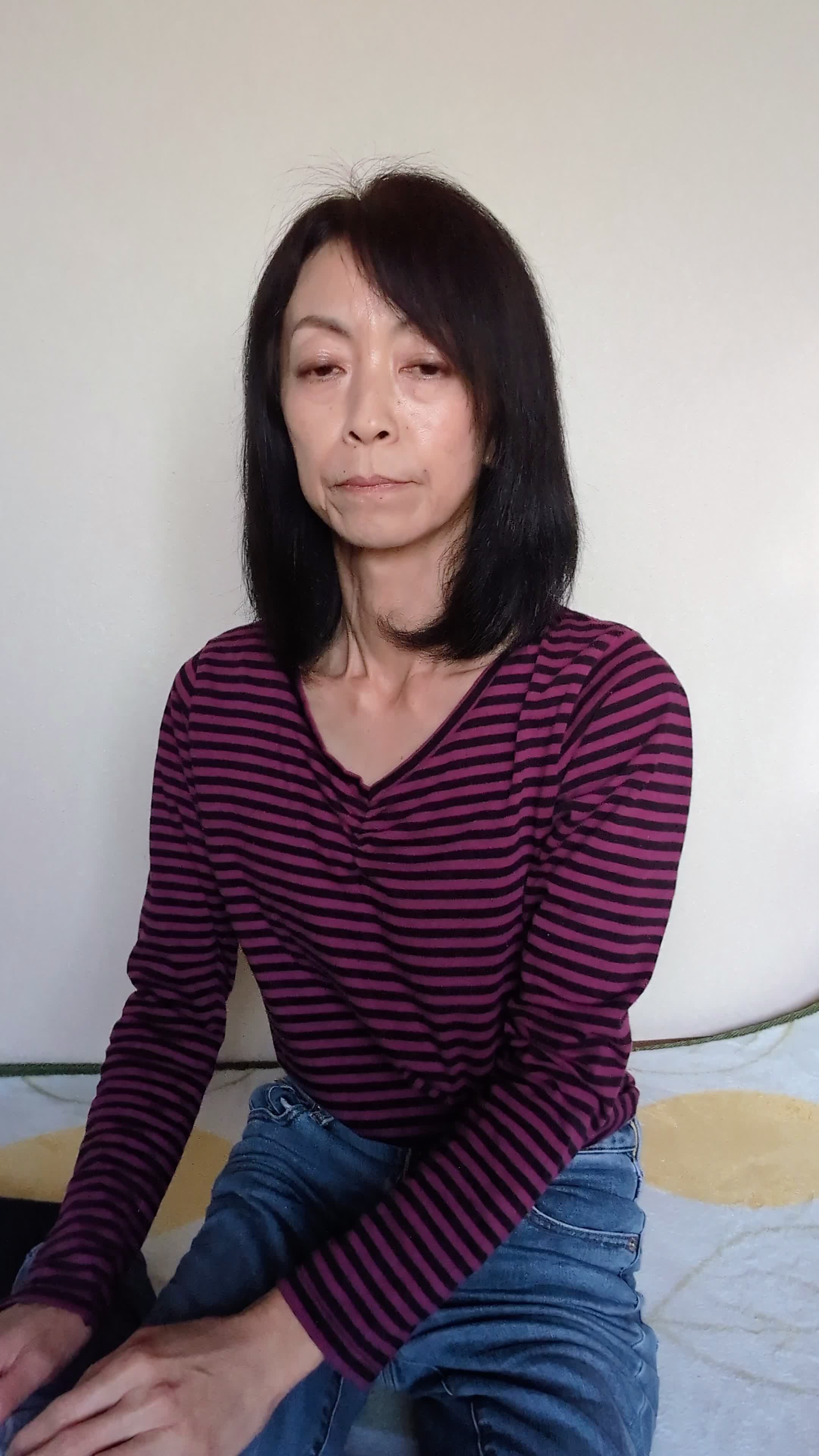 床に座り込み、自分のシャツを触りながら「このケアで変わるのかな」と考える仕草