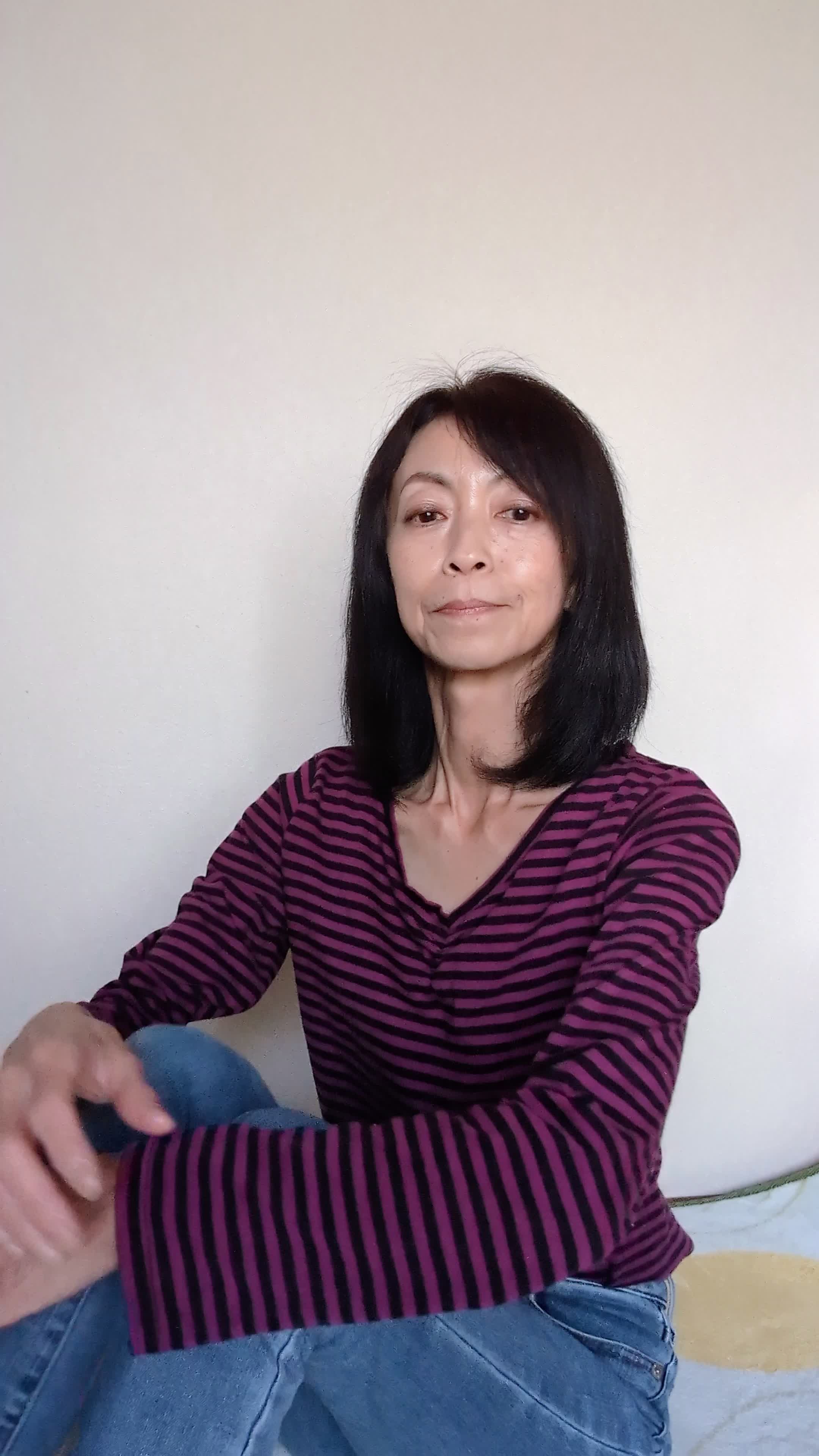 床で膝を立てて座り、「体臭が気にならない生活がどんな感じか想像する」微笑む姿