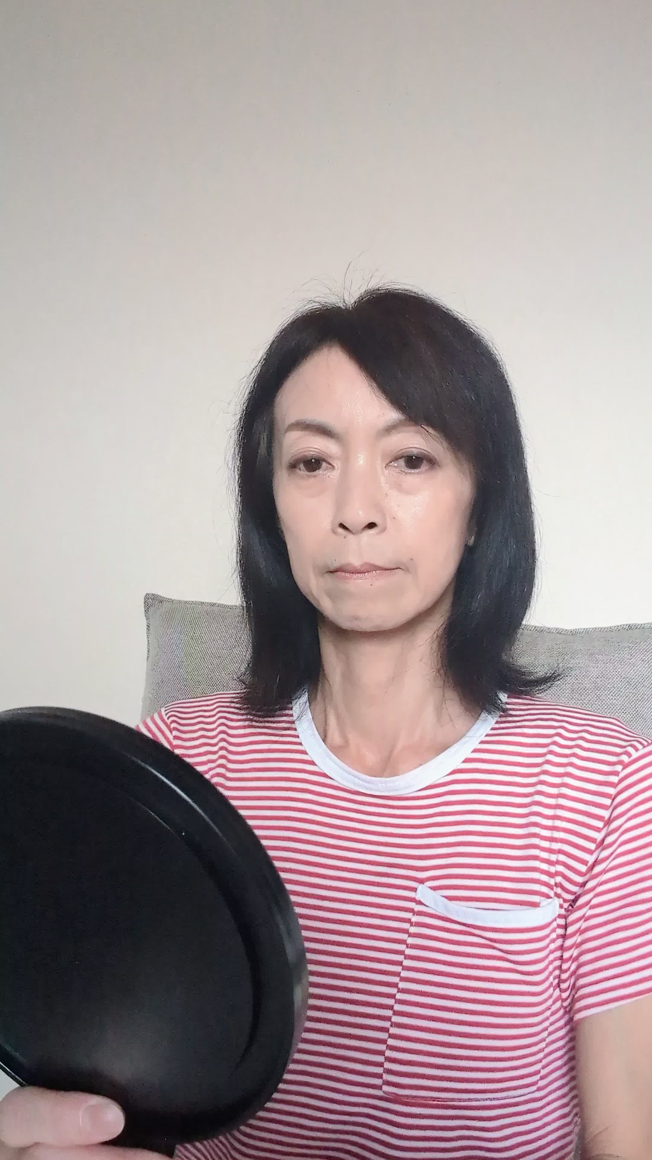 椅子に座り、鏡を見ながら白髪を気にして「どうにかならないかな」と悩む表情