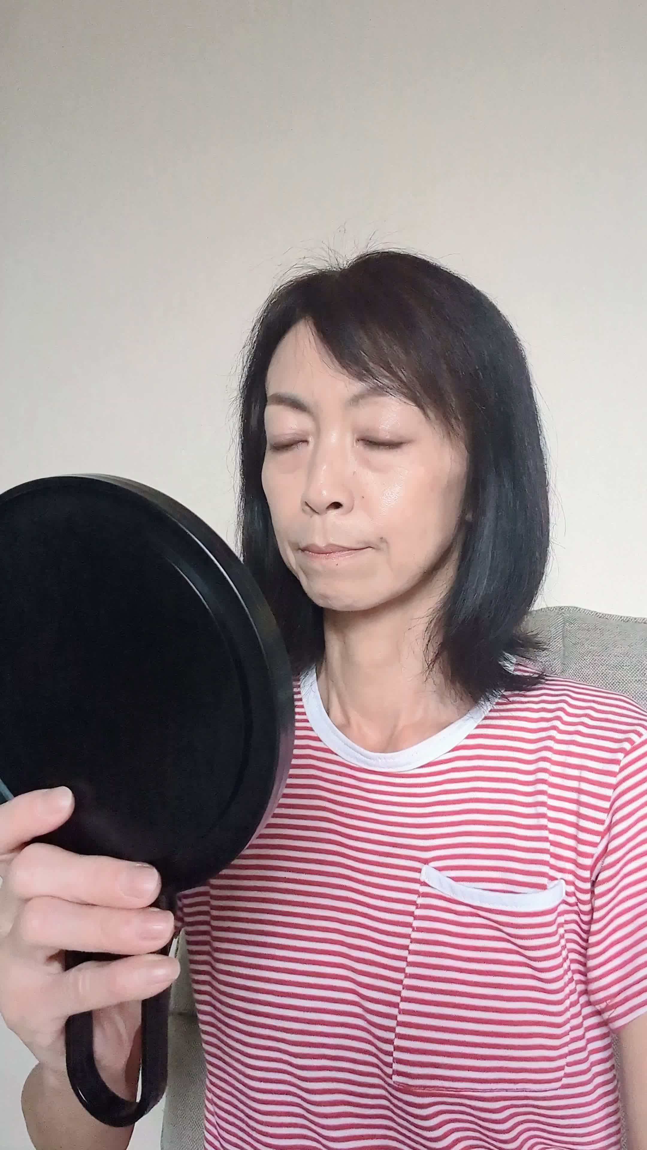 椅子に浅く腰掛け、鏡の前で「白髪部分を少し整える」動作