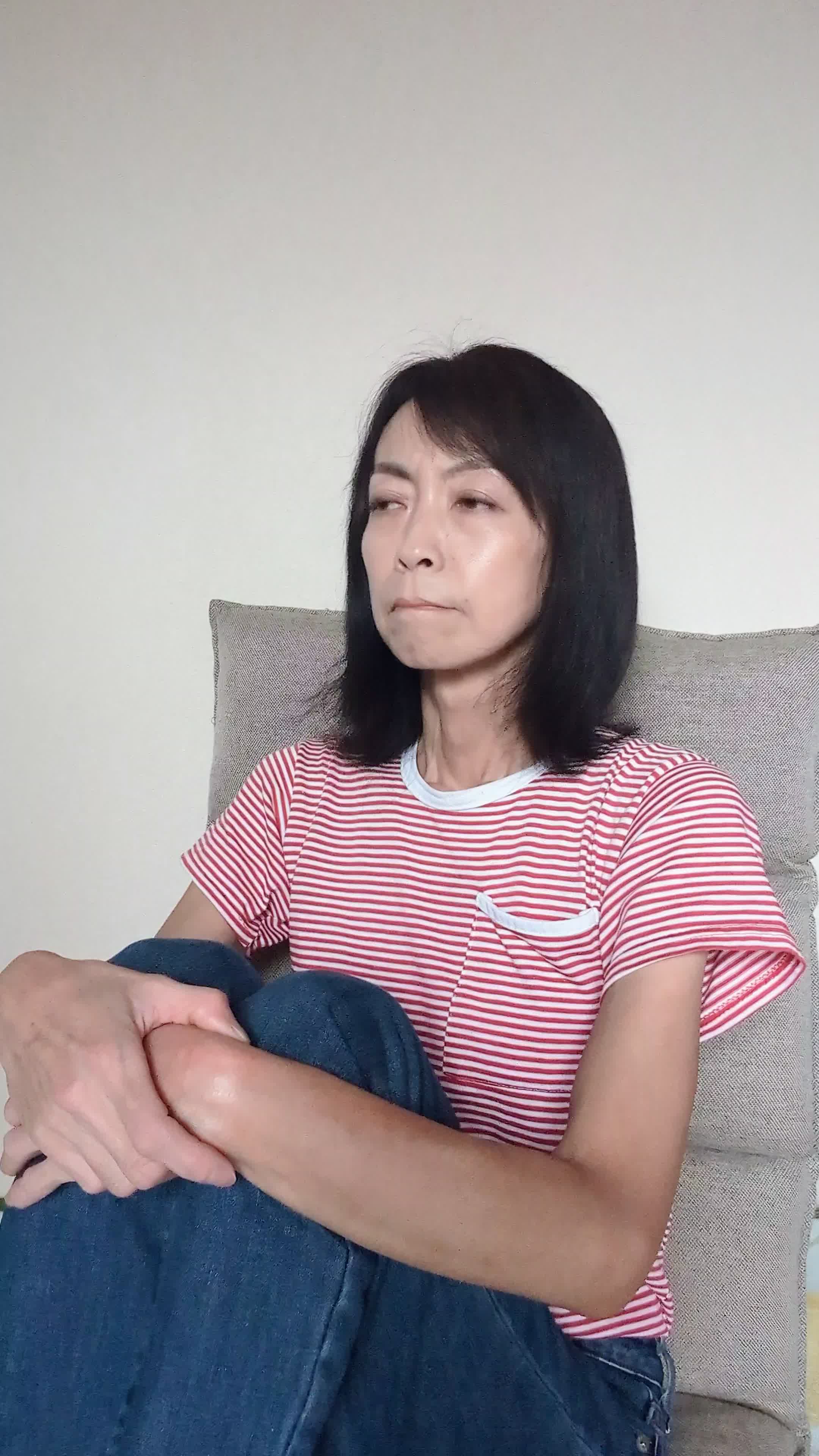 ソファで膝を抱え、「白髪が目立つのをどう隠すか考える」少し困った様子
