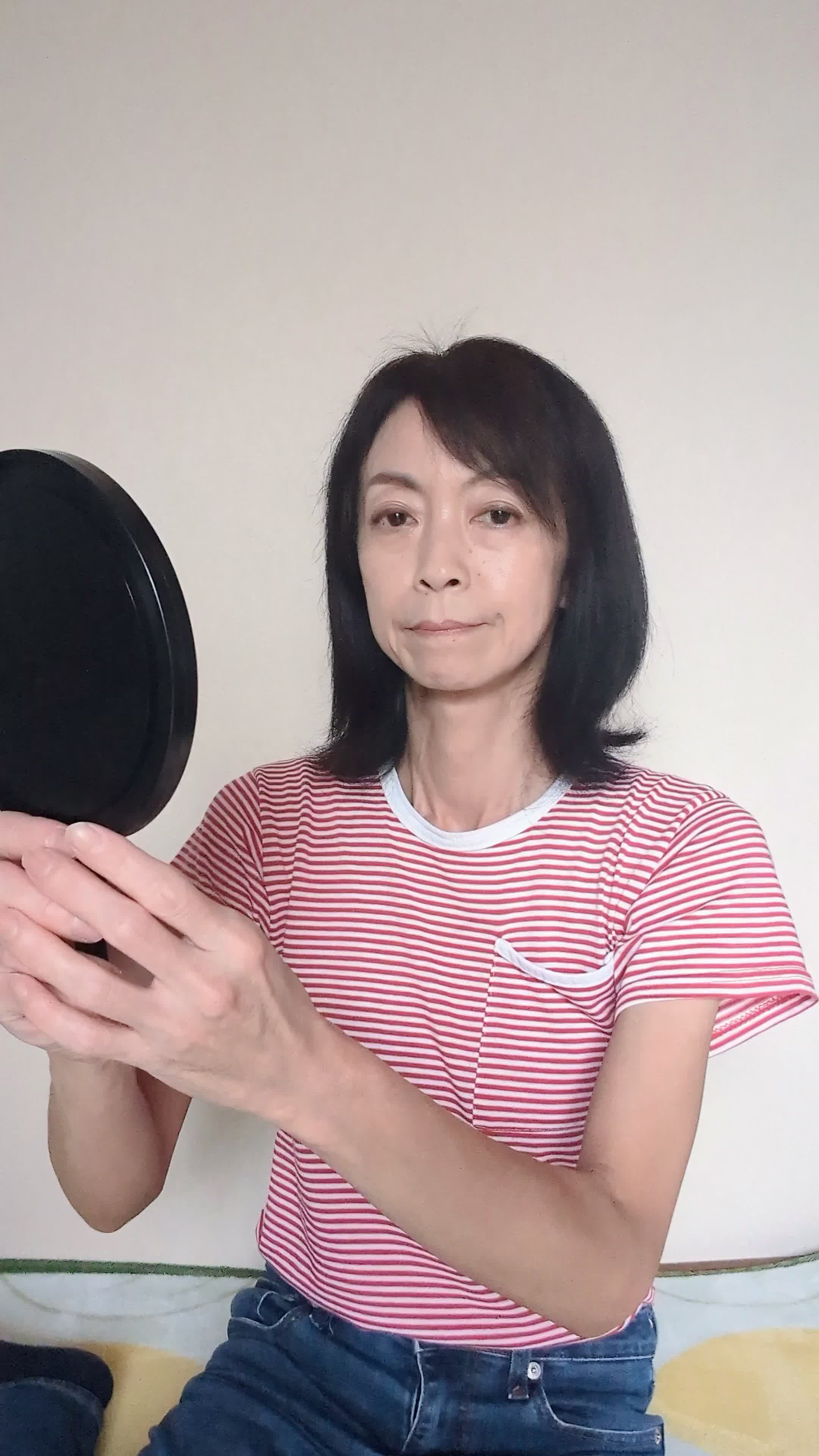 床に座り込み、鏡を近づけて白髪をじっくり確認し、「これがなくなれば…」と考える仕草