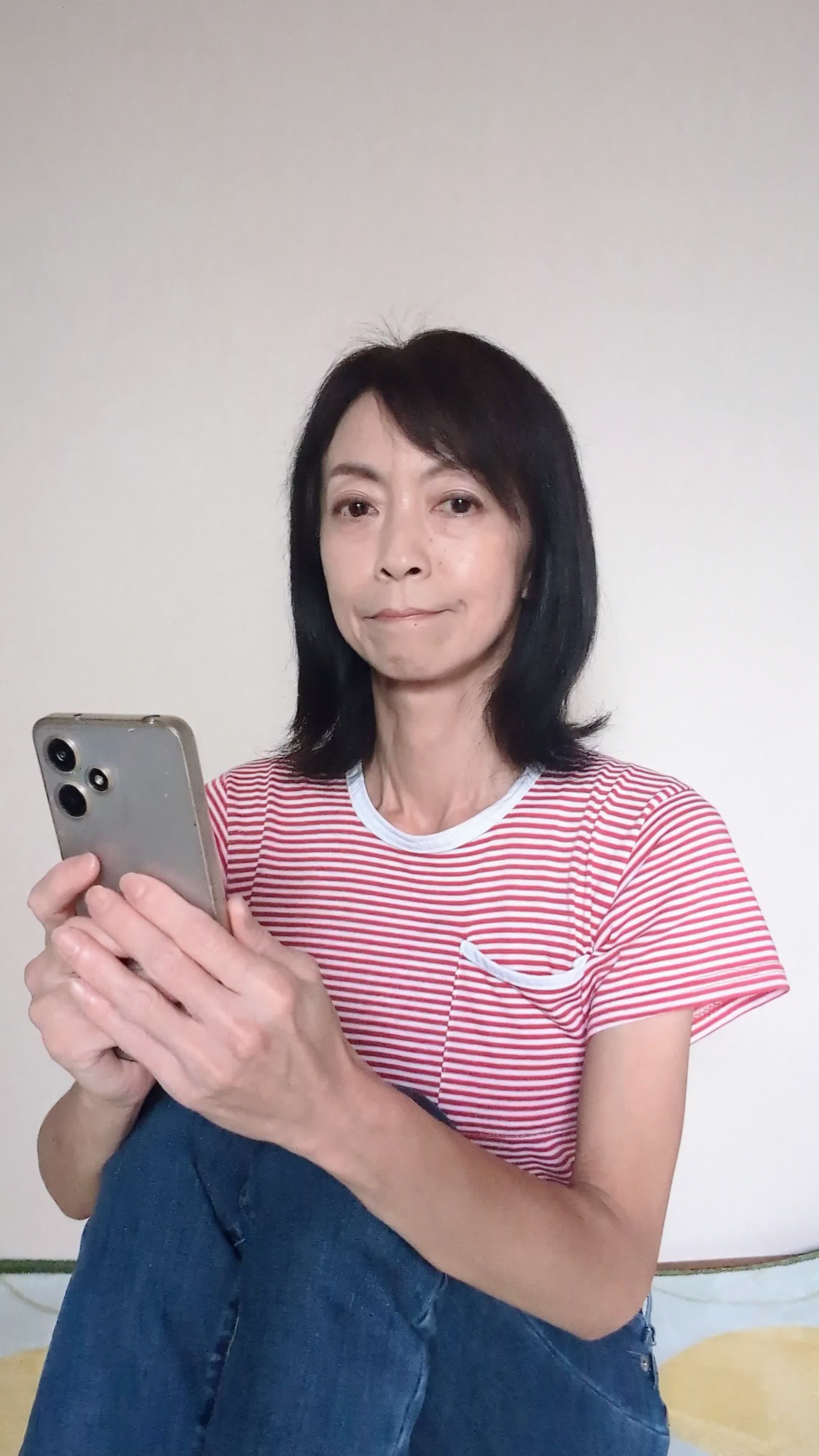 床で膝を立てて座り、「この白髪ケア商品を試してみようかな」と期待を込める動作