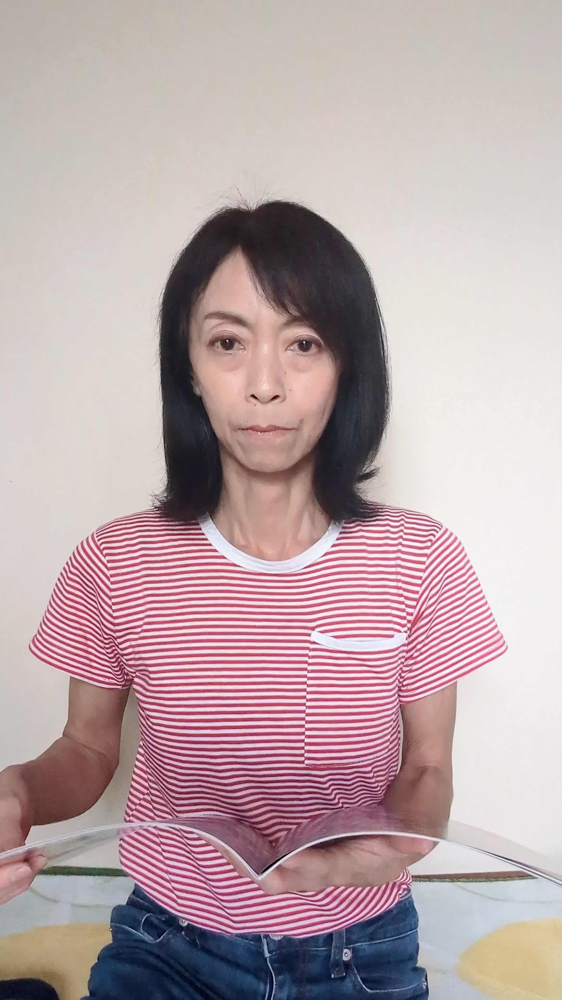床でカタログを眺め、「白髪ケアの商品をじっくり選んでいる」様子