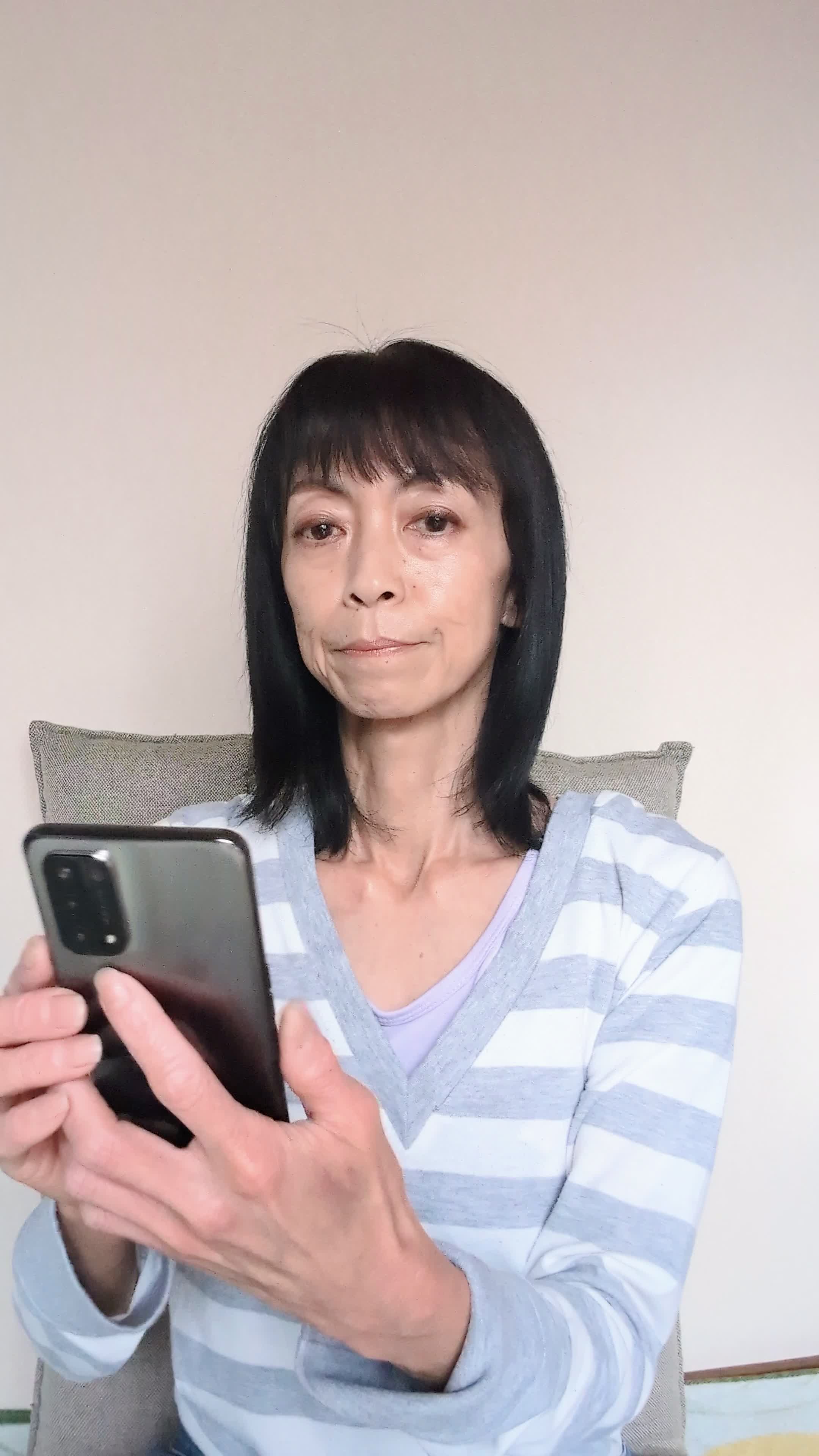 椅子に座り、スマホで求人情報を眺めながら「どれが自分に合うだろう」と悩む表情