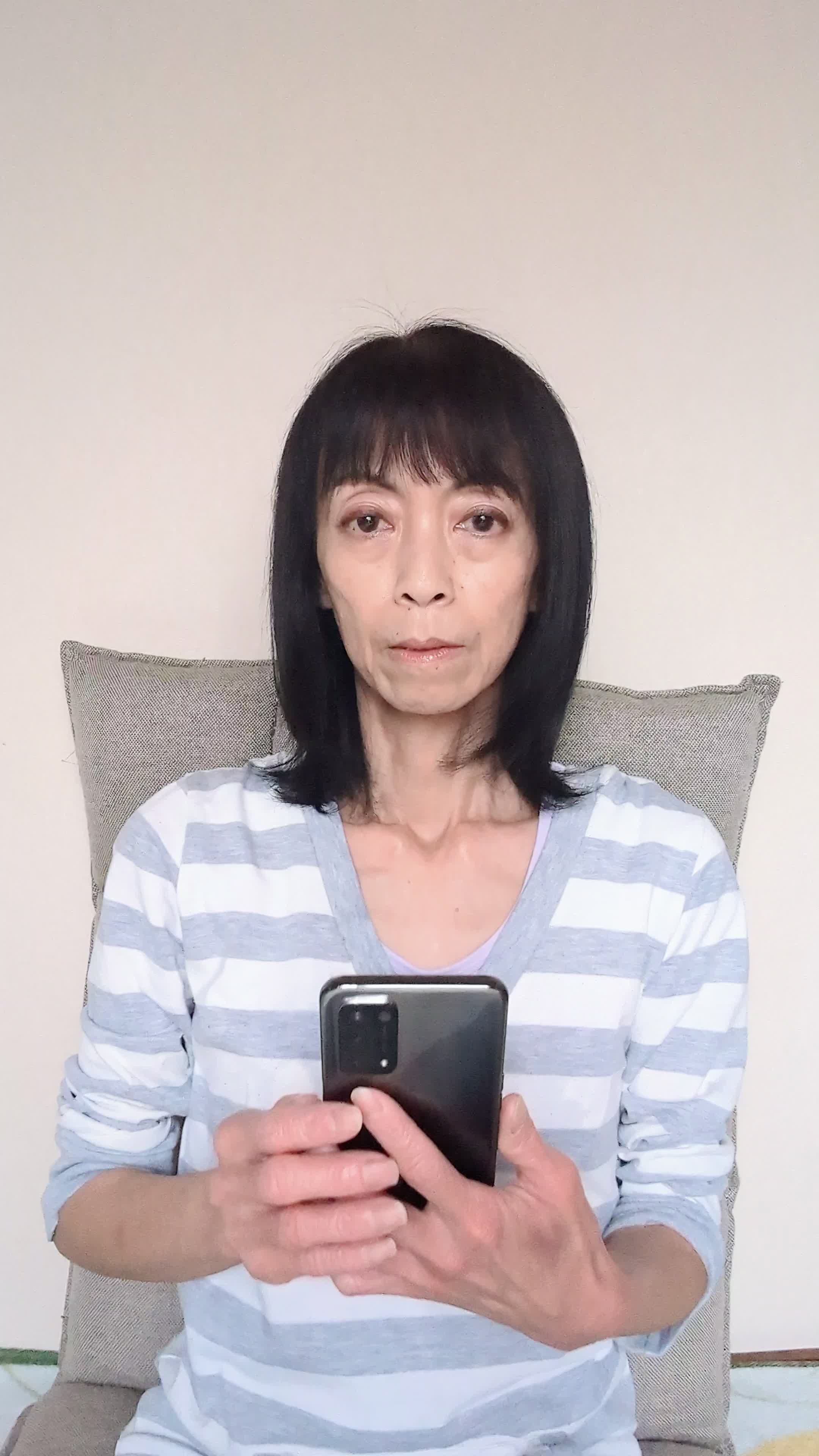 ソファでスマホを眺めながら、「応募結果を待ちながら少し緊張する」表情