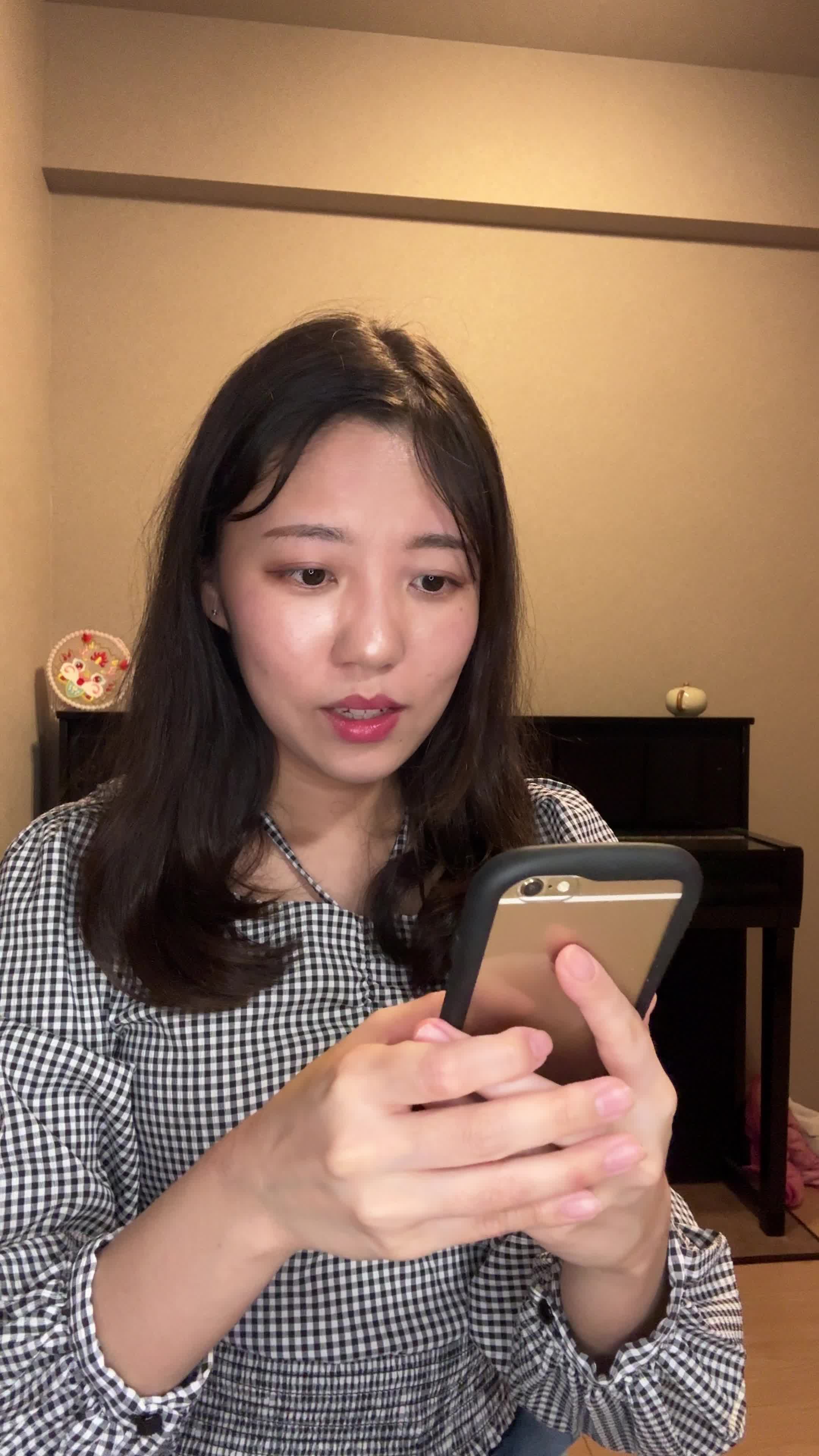椅子に腰掛け、スマホの画面を見て「白髪ケアの口コミを読んで納得する」表情