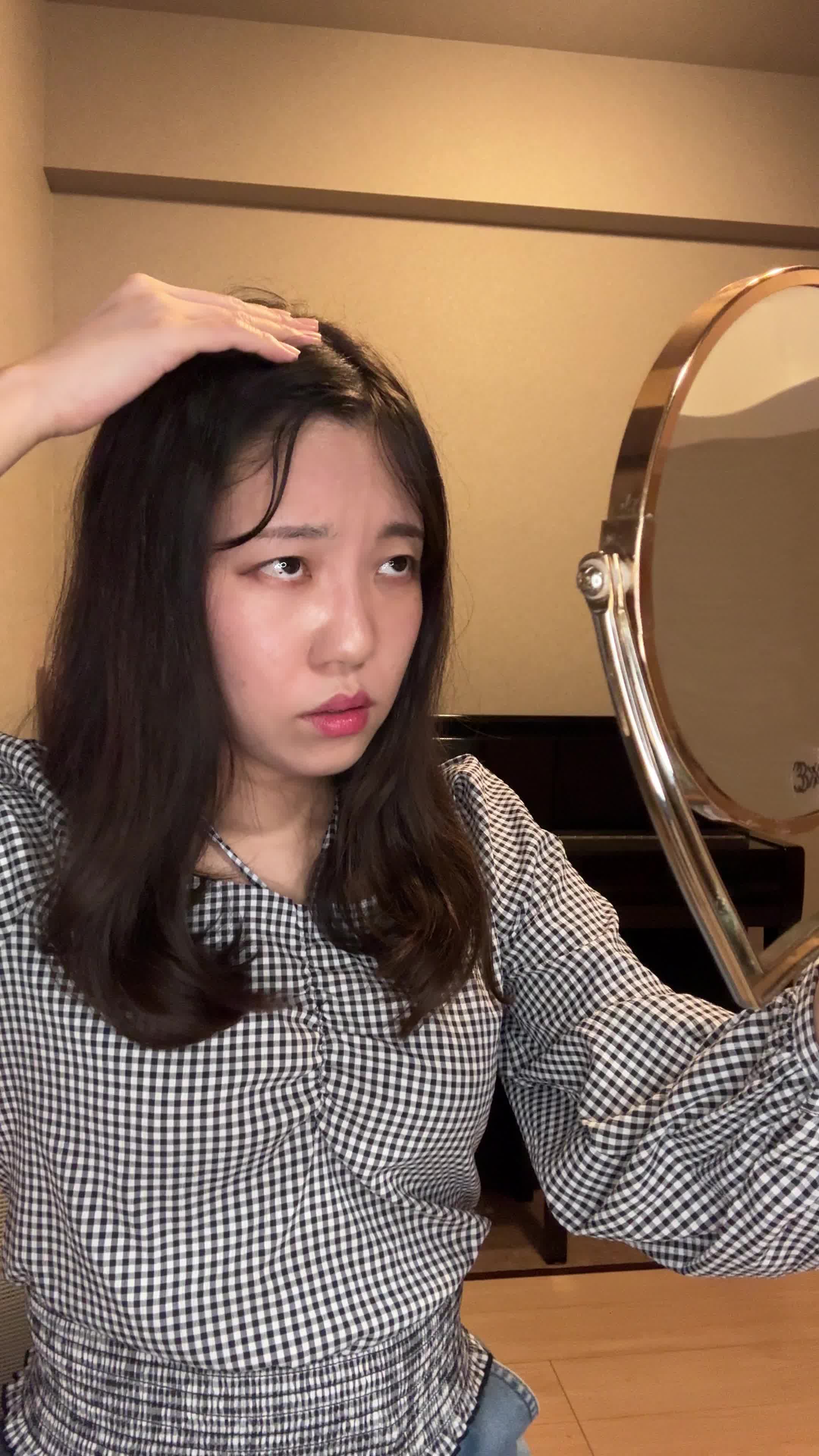 椅子に座り、鏡を見ながら白髪を気にして「どうにかならないかな」と悩む表情