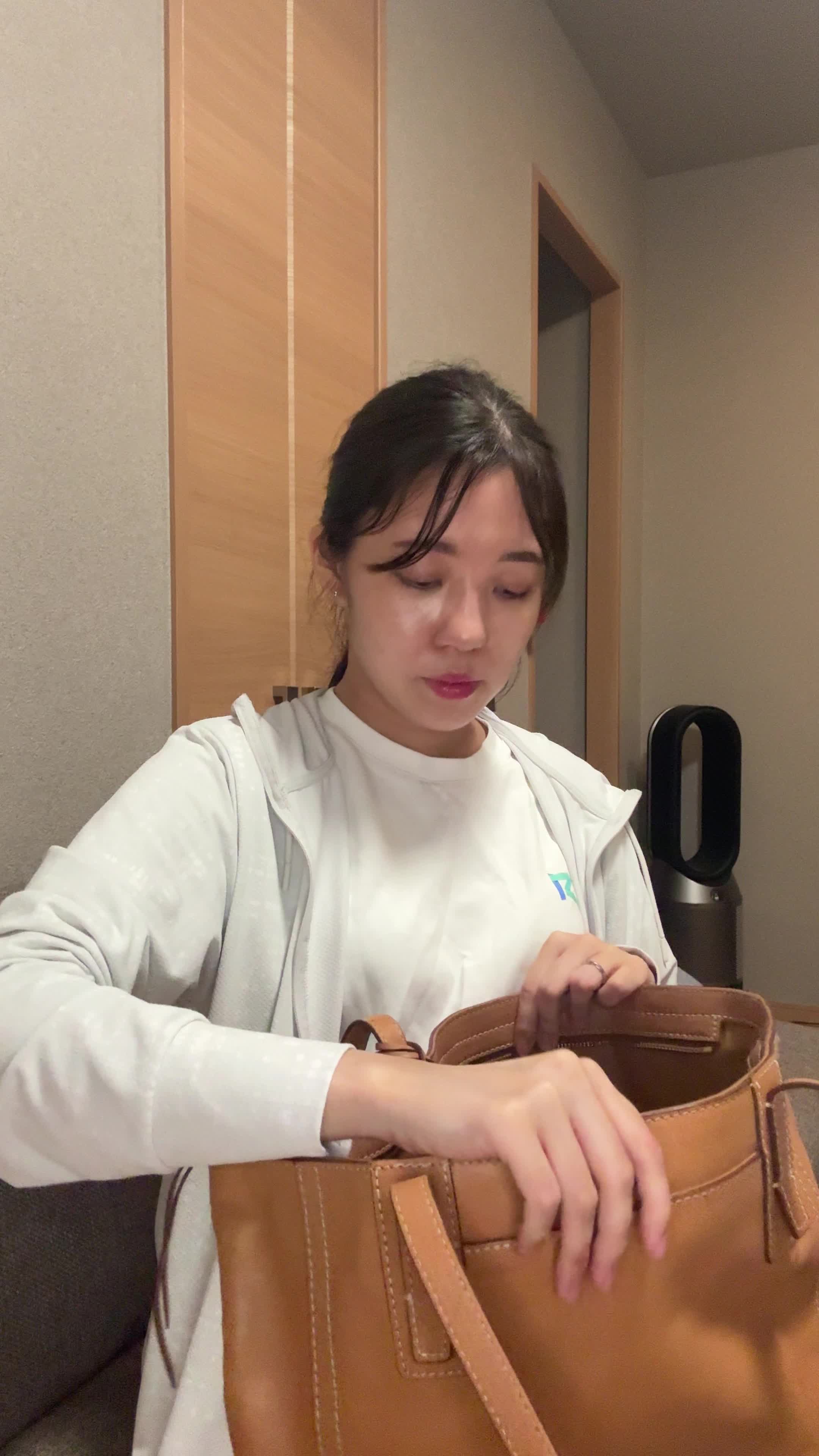 ソファでカバンの中を確認しながら、「体臭ケアスプレーを常備する」様子