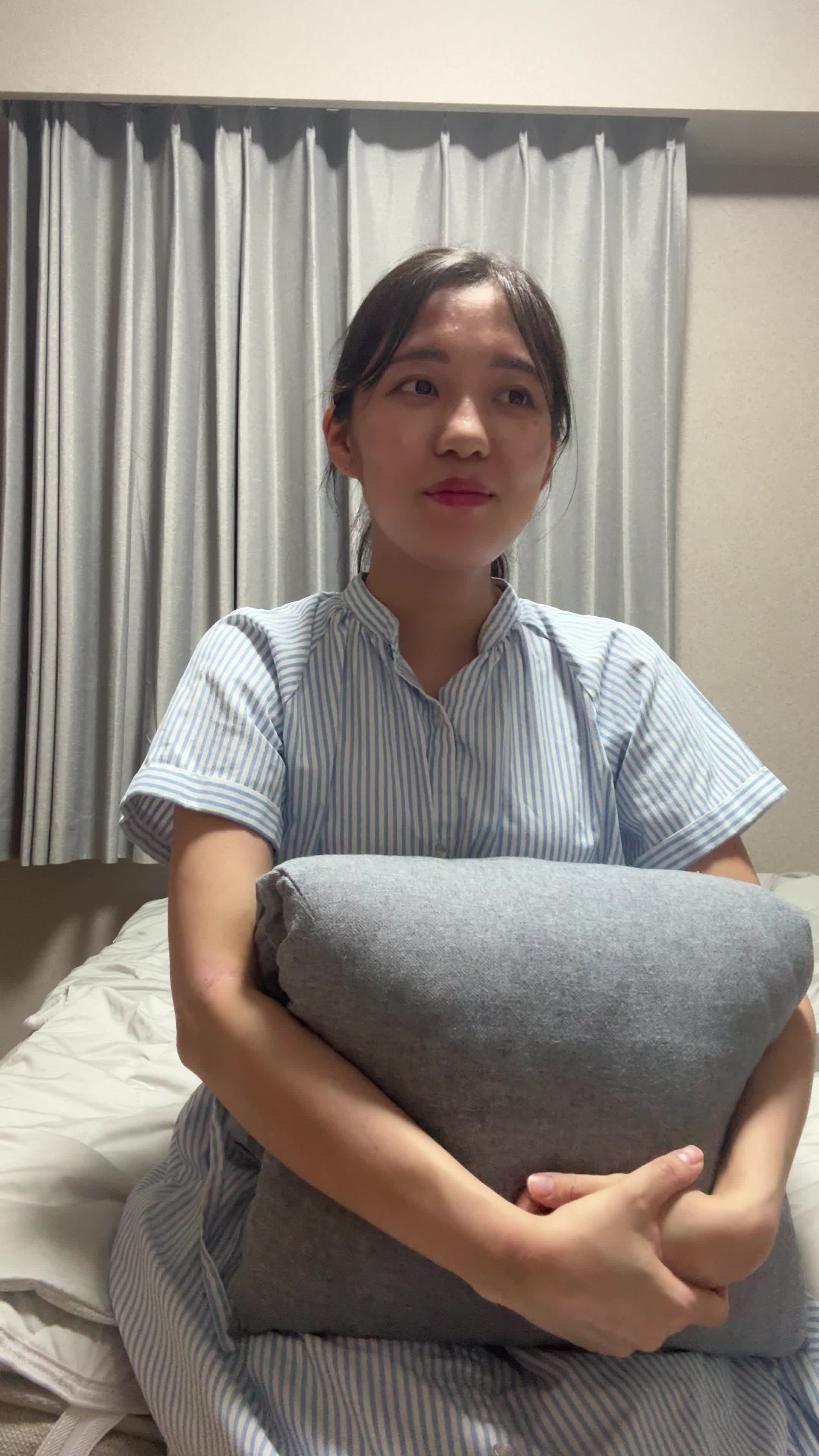 ベッドでクッションを抱え、「新しいチャレンジにワクワクする」様子