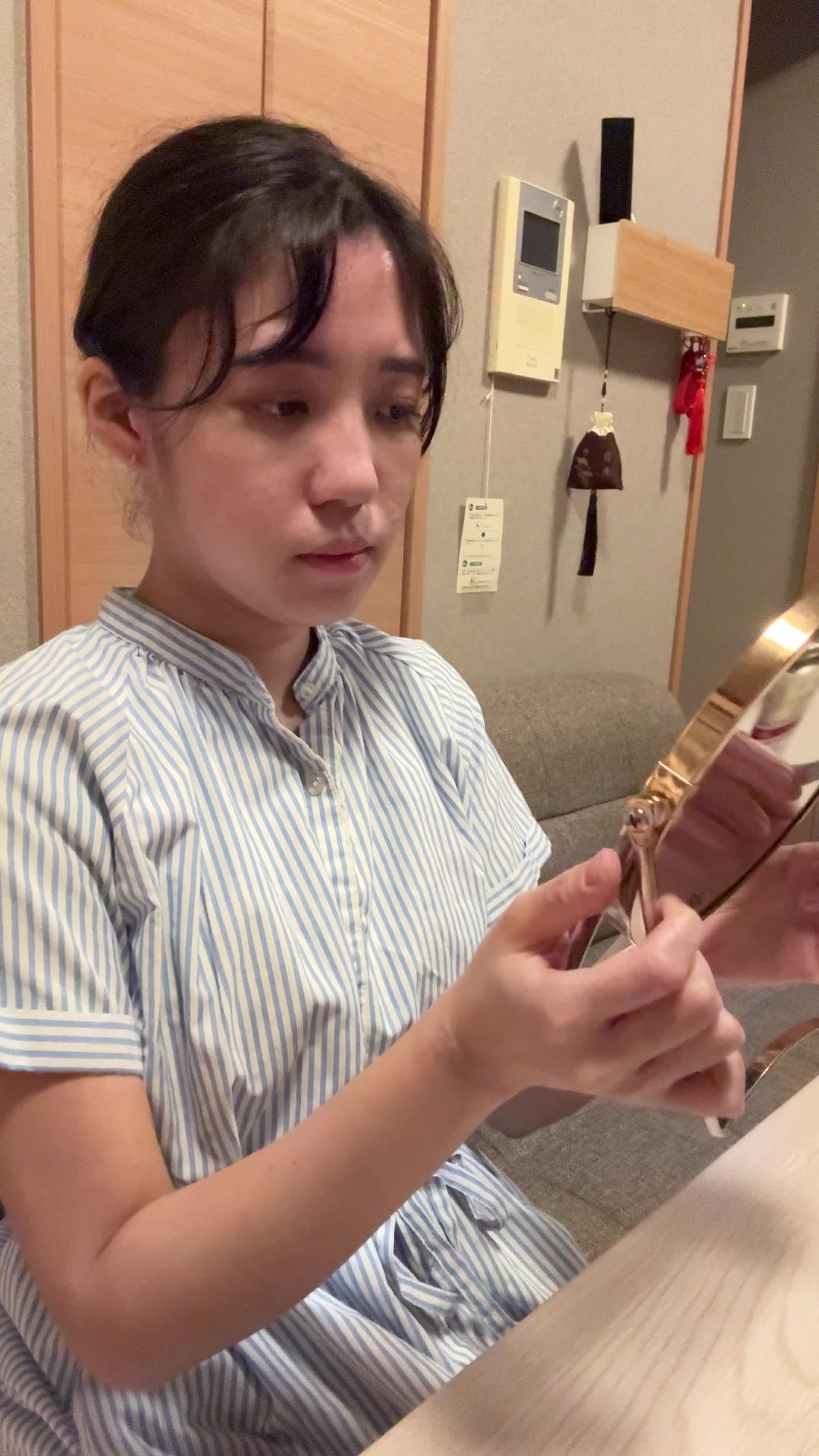 テーブルで鏡を見ながら、「顔色が悪くて腸の不調のせいかも」と気にする様子