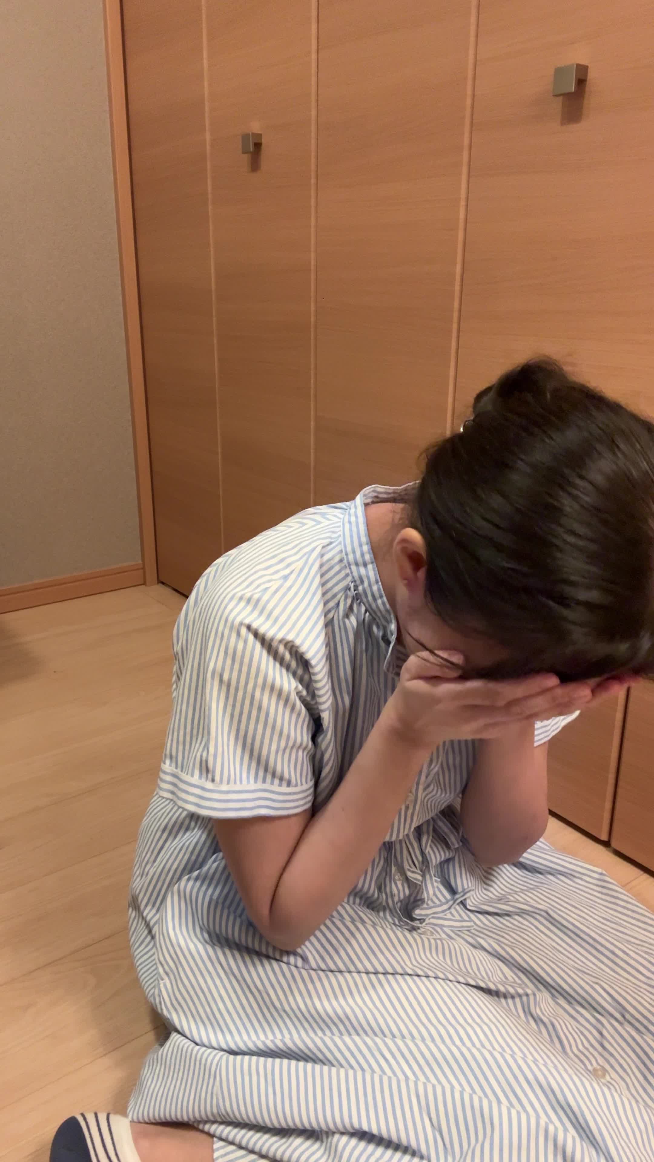 床で顔を両手で覆い、「腸の不調が続くせいで疲れが取れない」と落ち込む表情