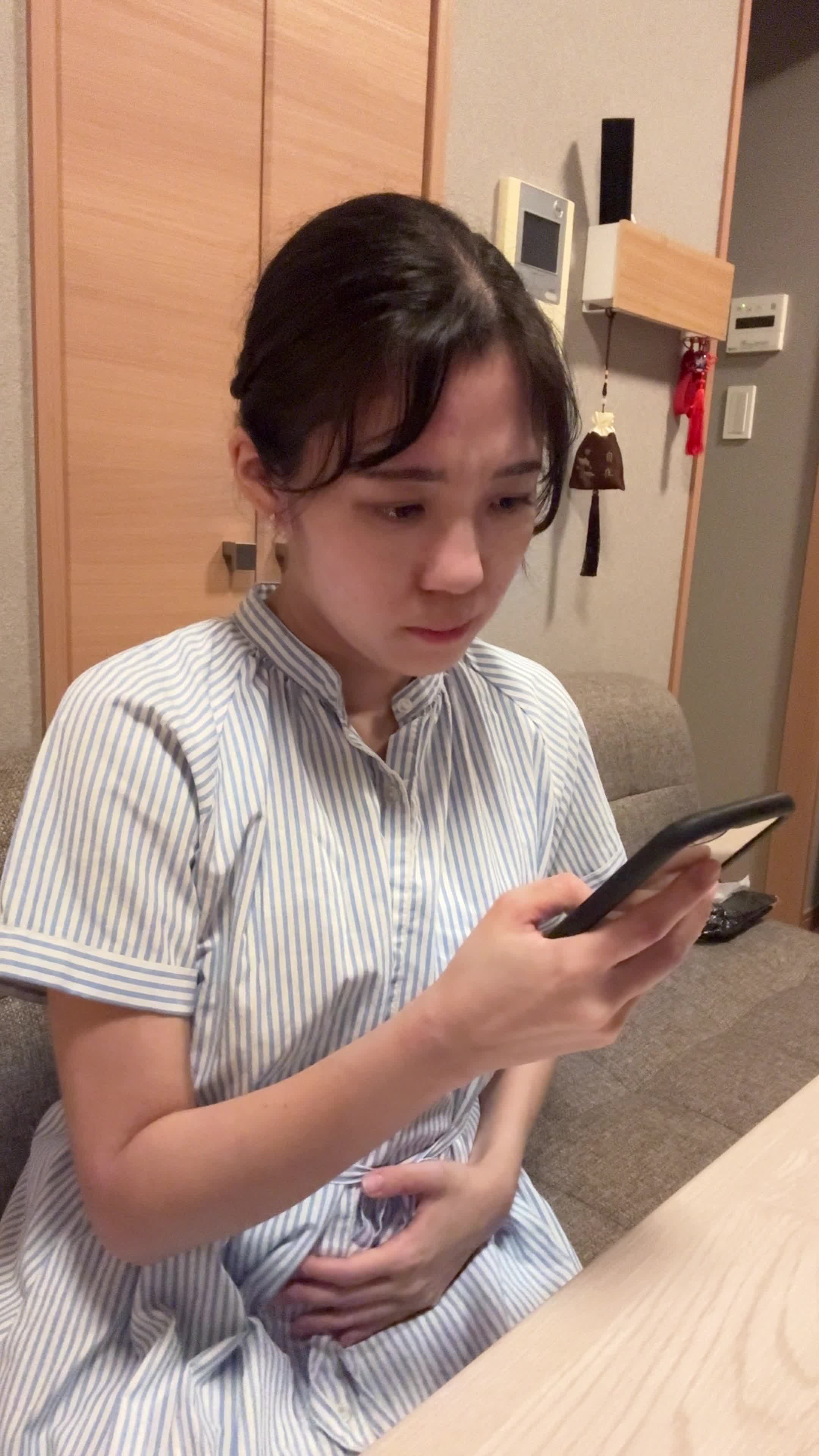 テーブルでスマホを見ながら、「便秘の原因を検索して悩む」真剣な表情