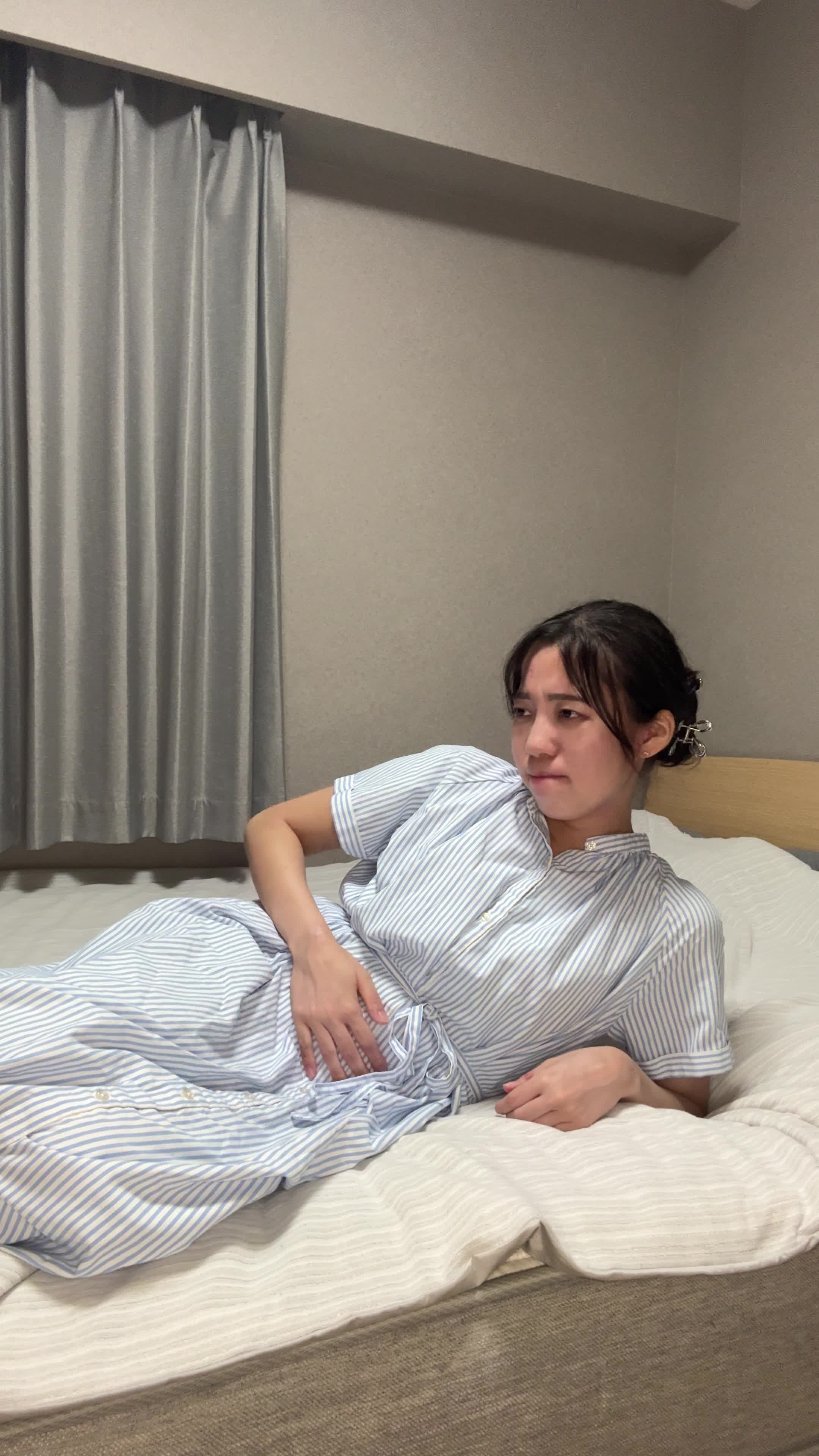ベッドで横になり、「また便秘が続いている…」と眉をひそめて悩む表情