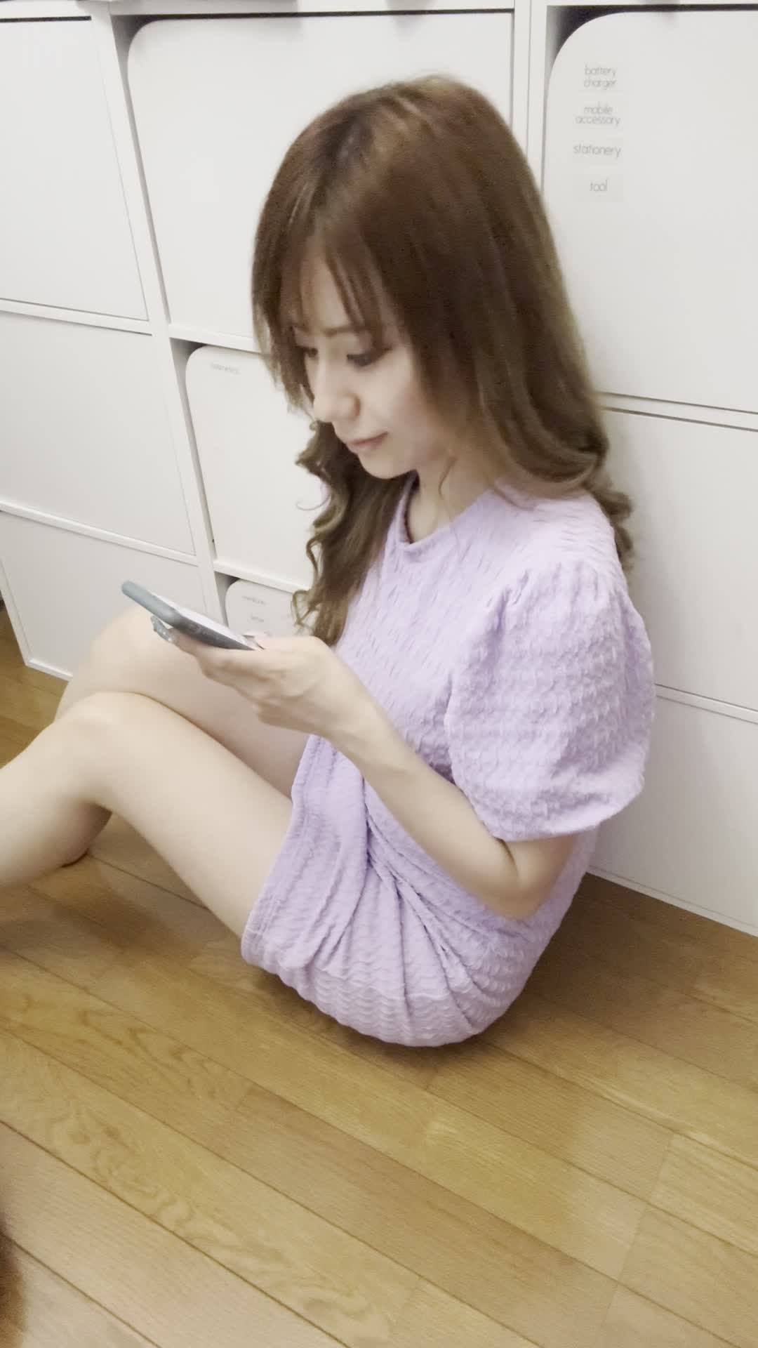 床に座り込み、スマホで商品画像を見て「このデザイン素敵！」と微笑む仕草