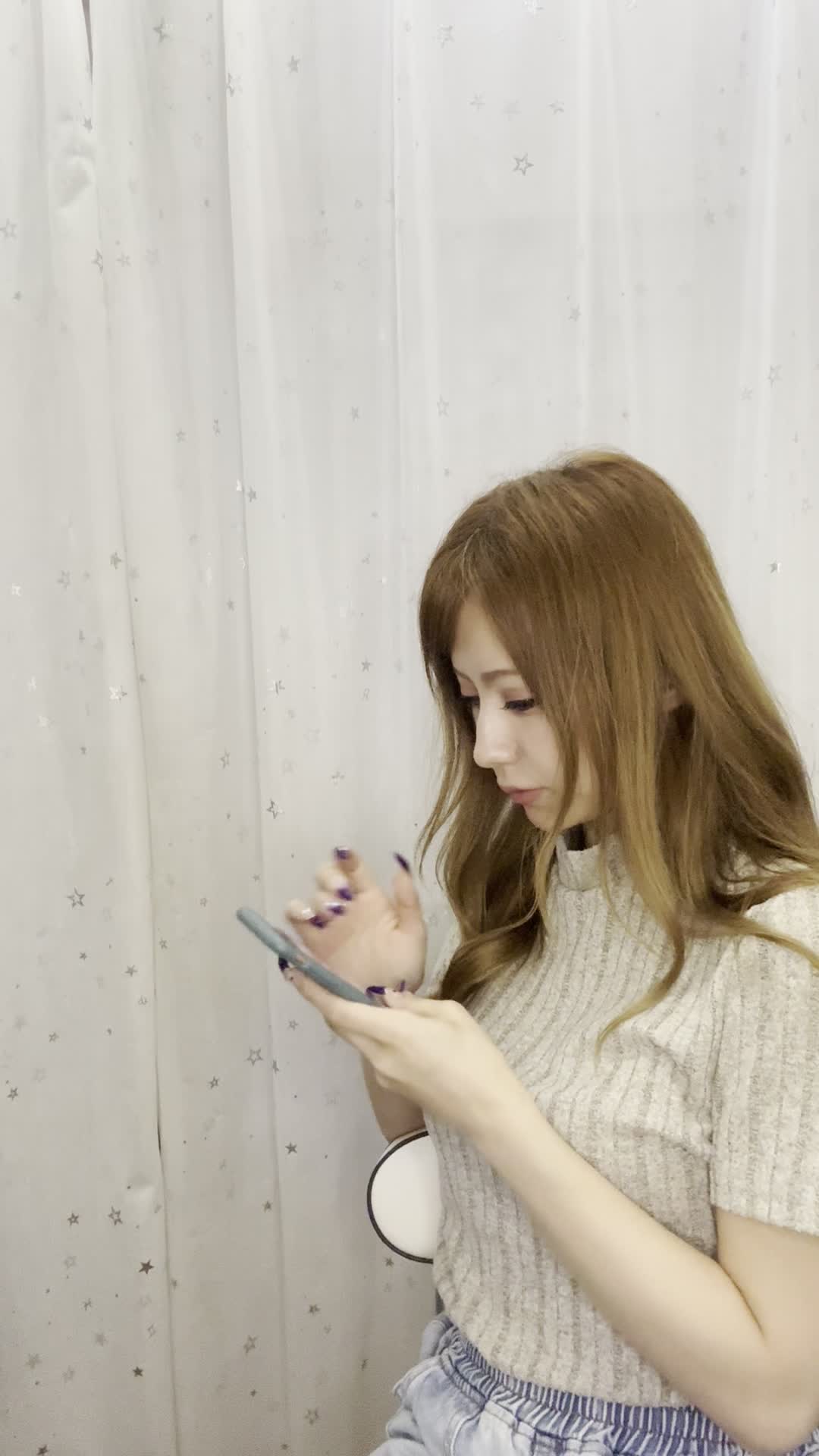 椅子に腰掛け、スマホの画面を見て「白髪ケアの口コミを読んで納得する」表情