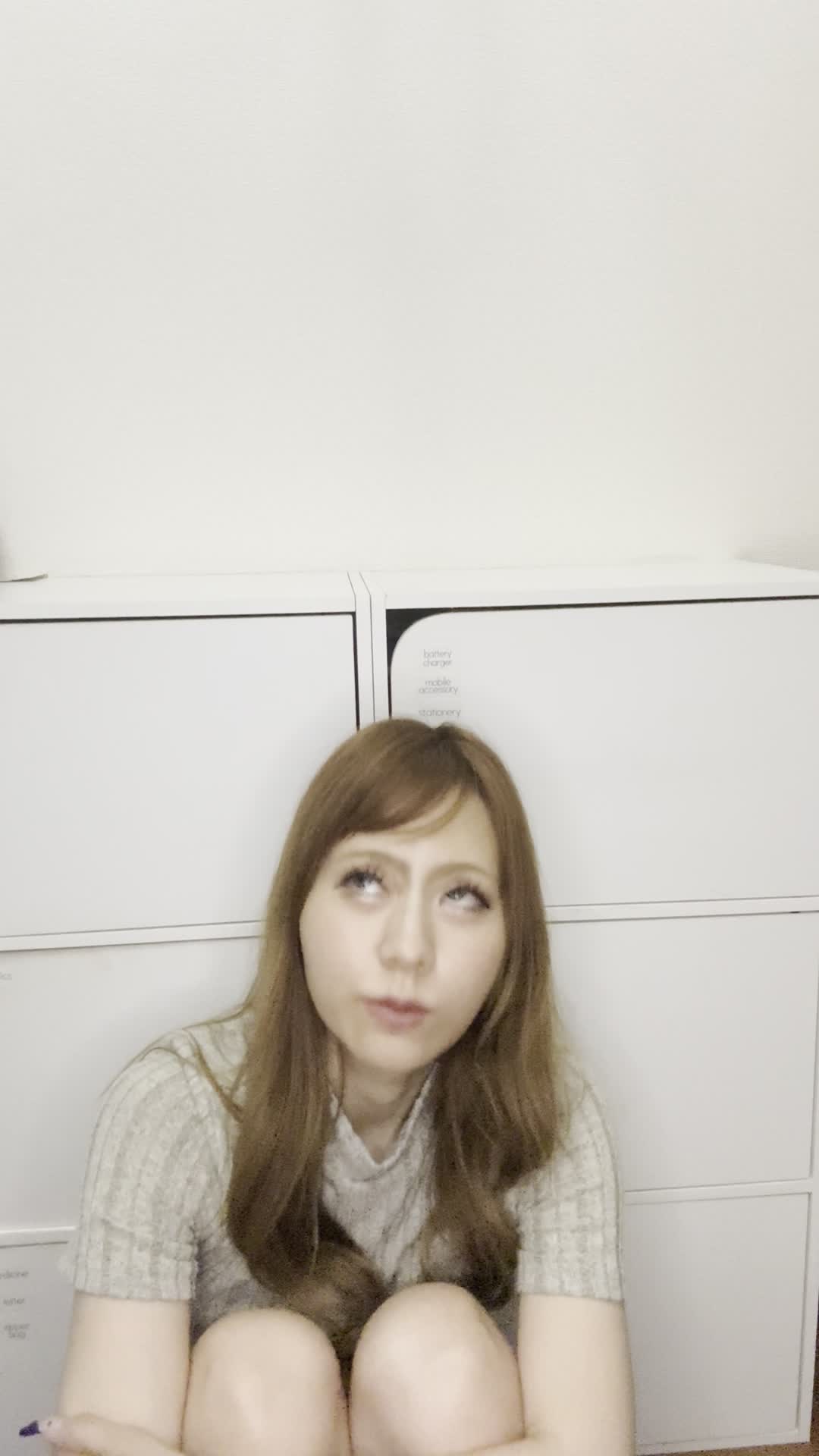 床で膝を立てて座り、「この白髪ケア商品を試してみようかな」と期待を込める動作