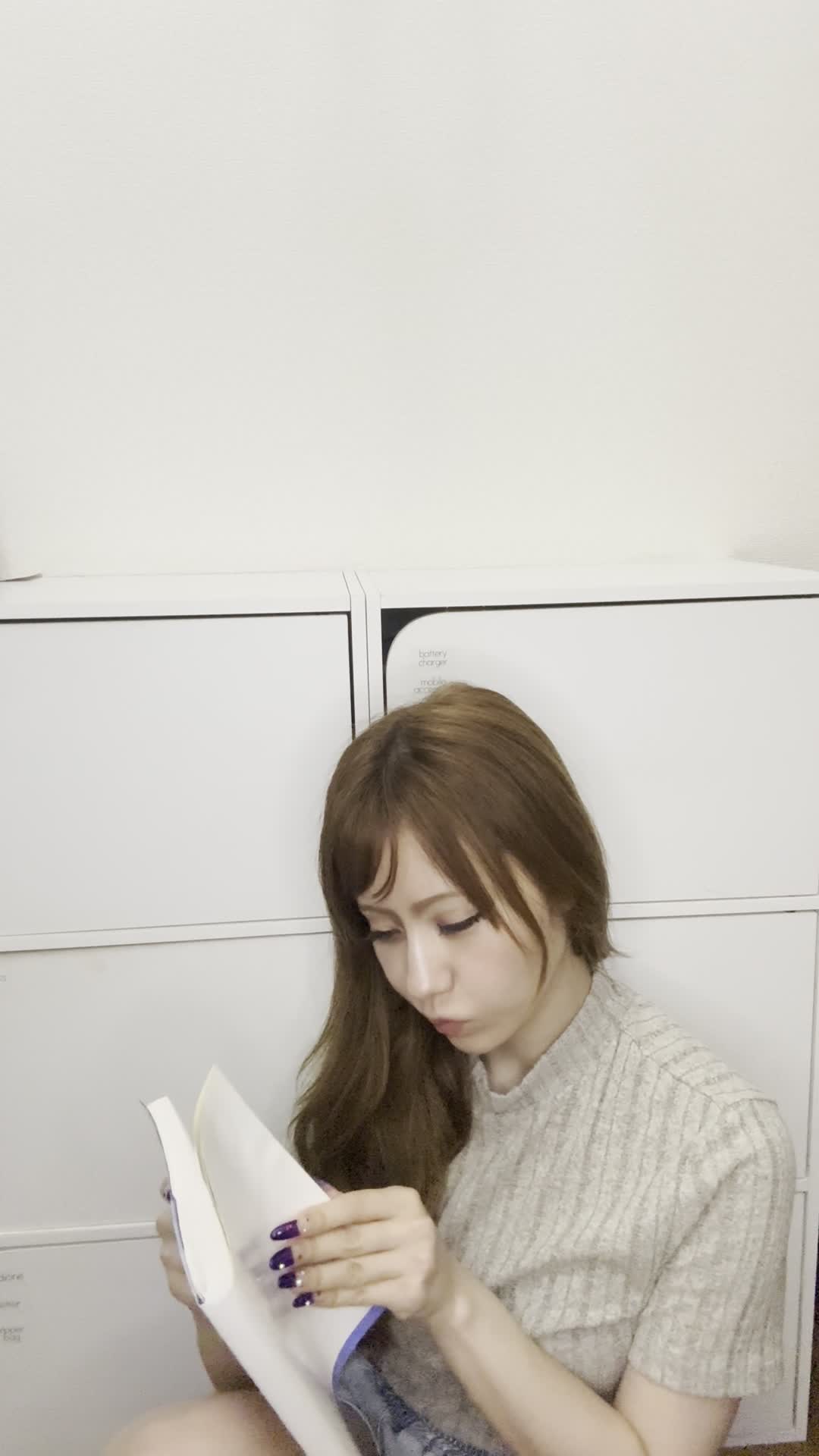 床でカタログを眺め、「白髪ケアの商品をじっくり選んでいる」様子