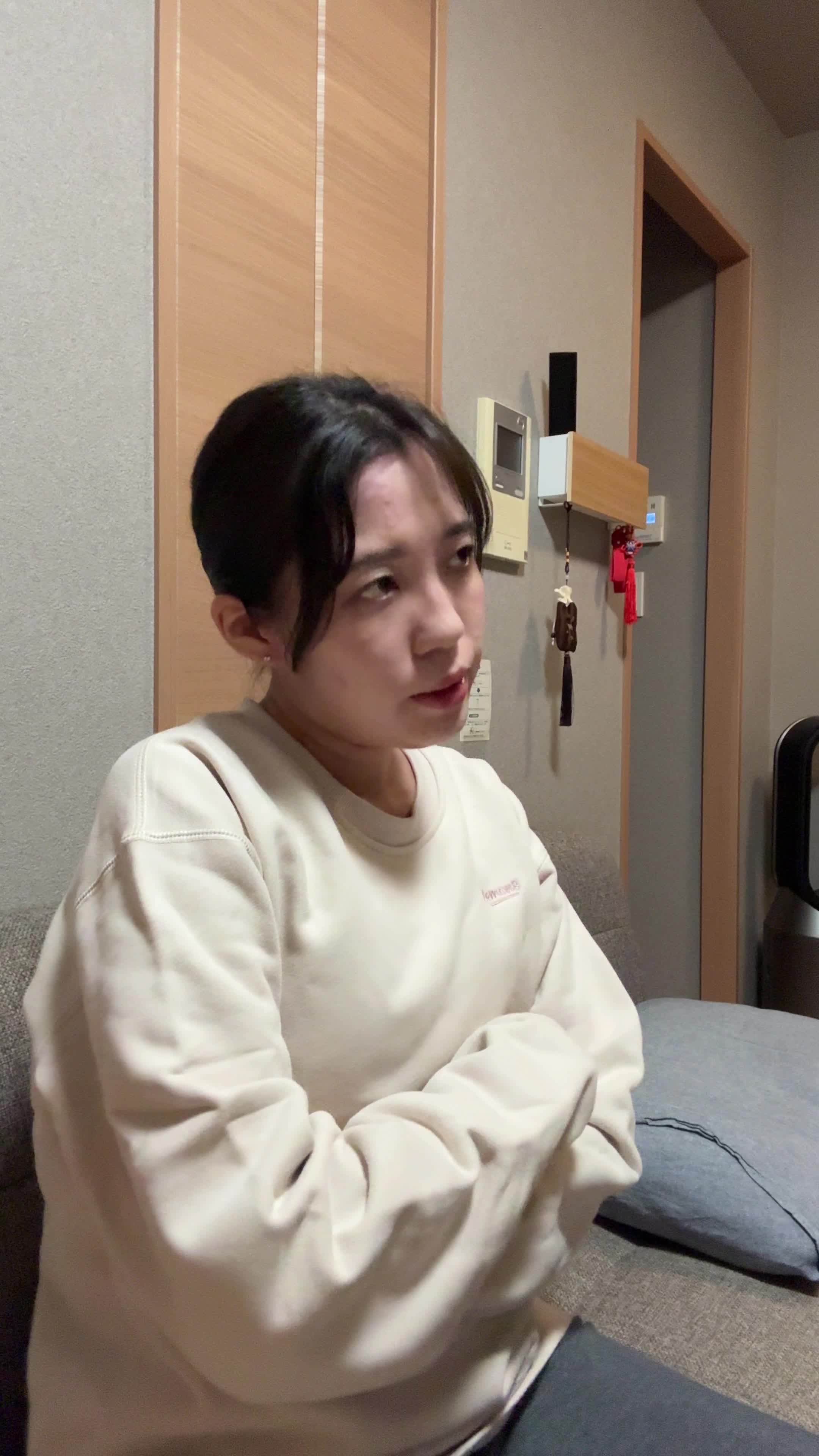 ソファで膝を抱え、「疲れやすくて何もする気が起きない」とため息をつく様子