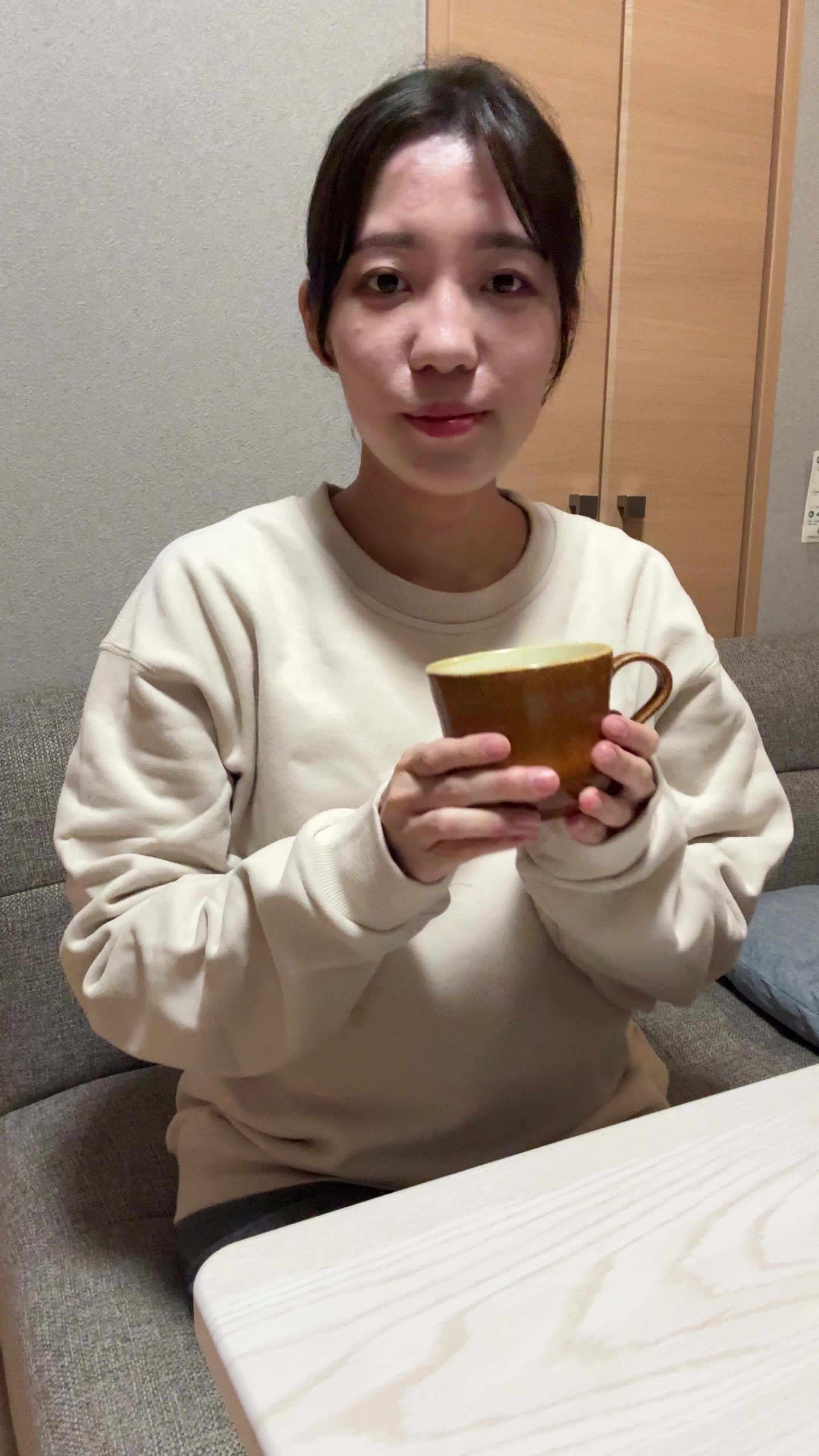 テーブルで飲み物を手に取り、「これで改善するなら試したい」と期待する微笑み