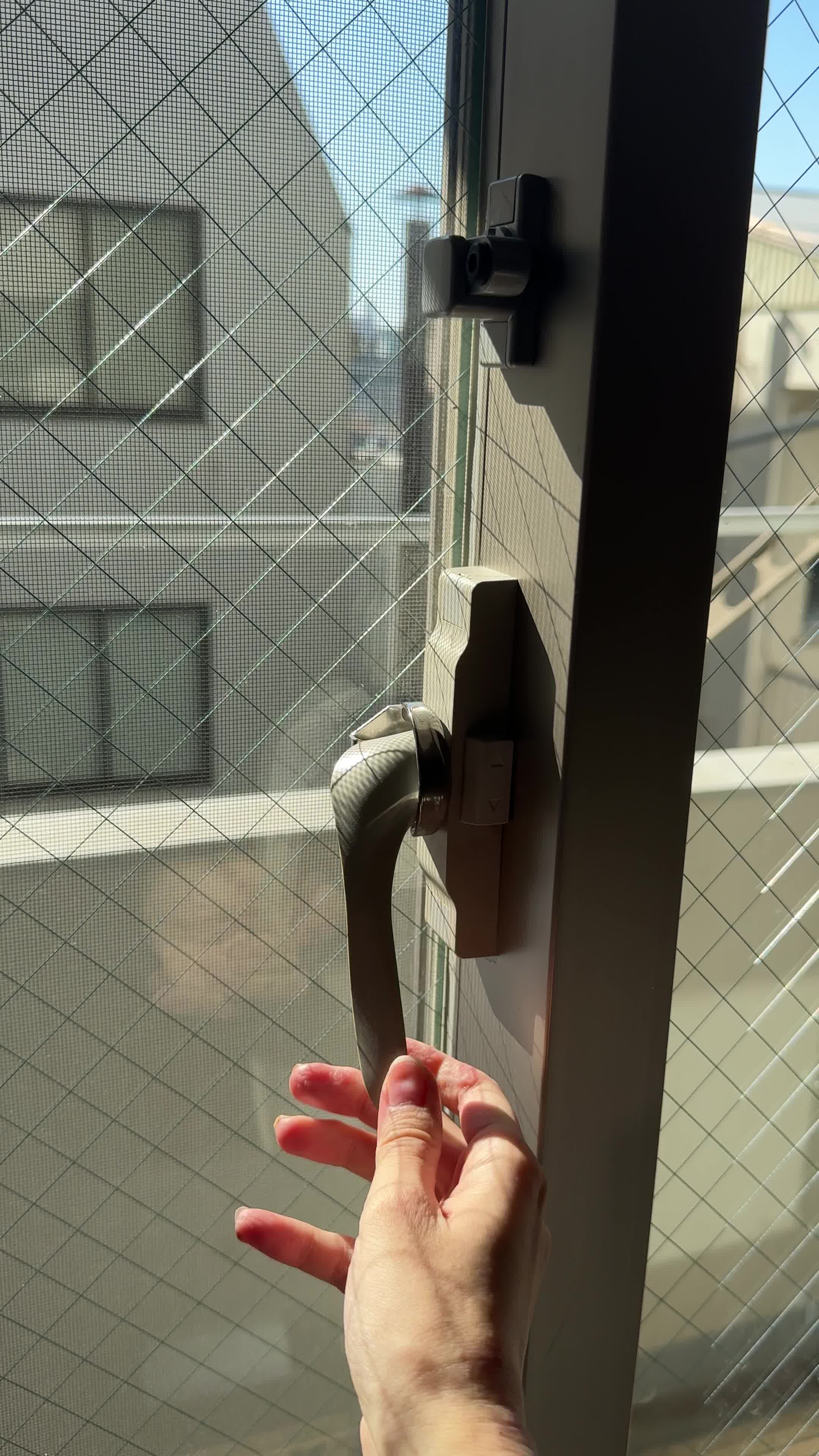 窓の鍵をゆっくり回して開閉する仕草