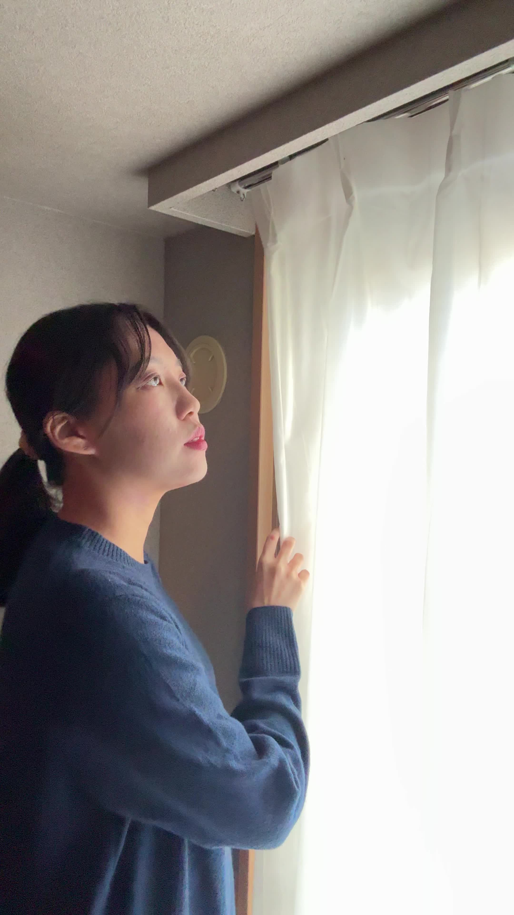 窓際に立って、カーテンを動かす仕草