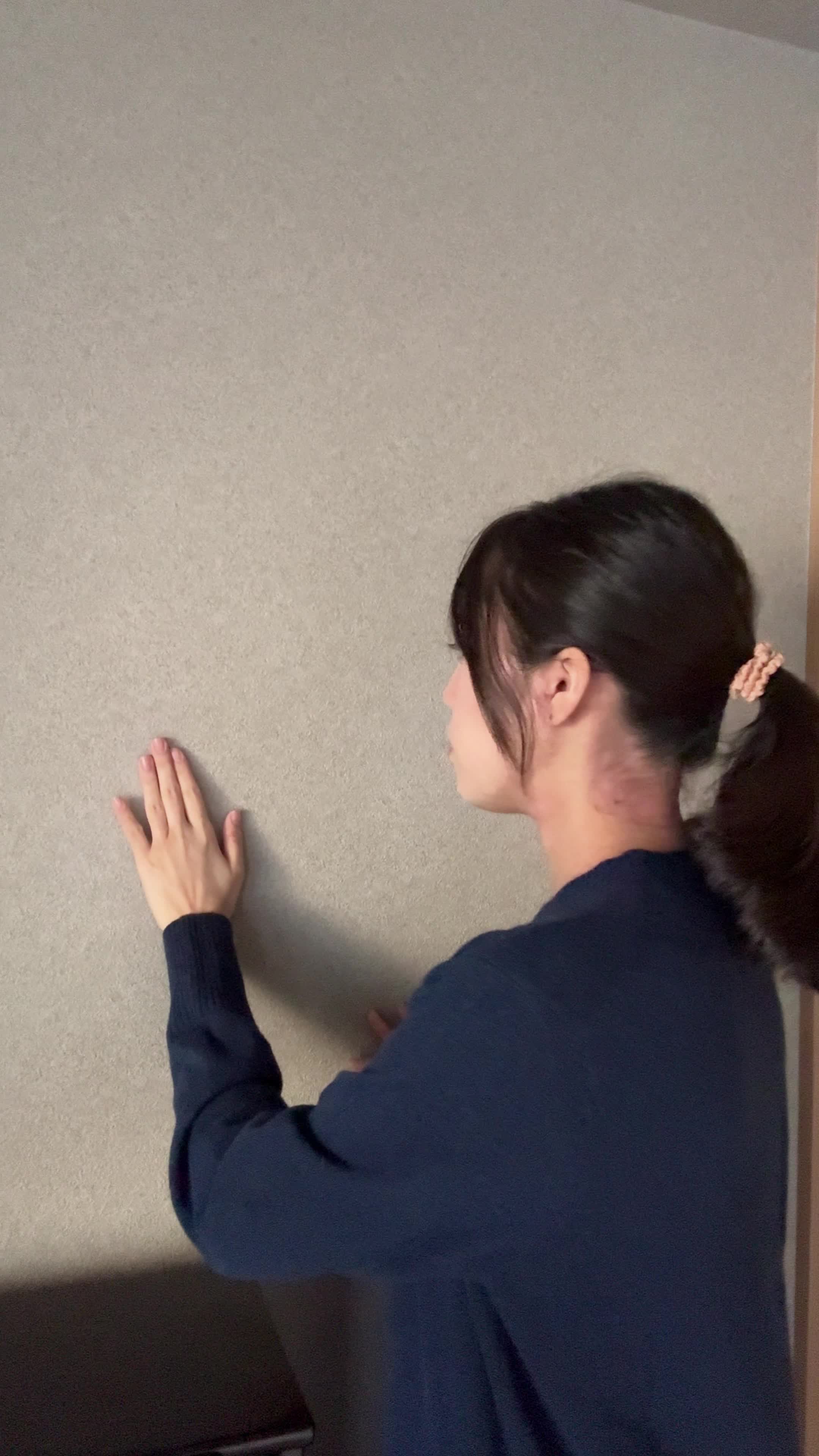 壁に近づいて手で触れ、じっと観察するような動作