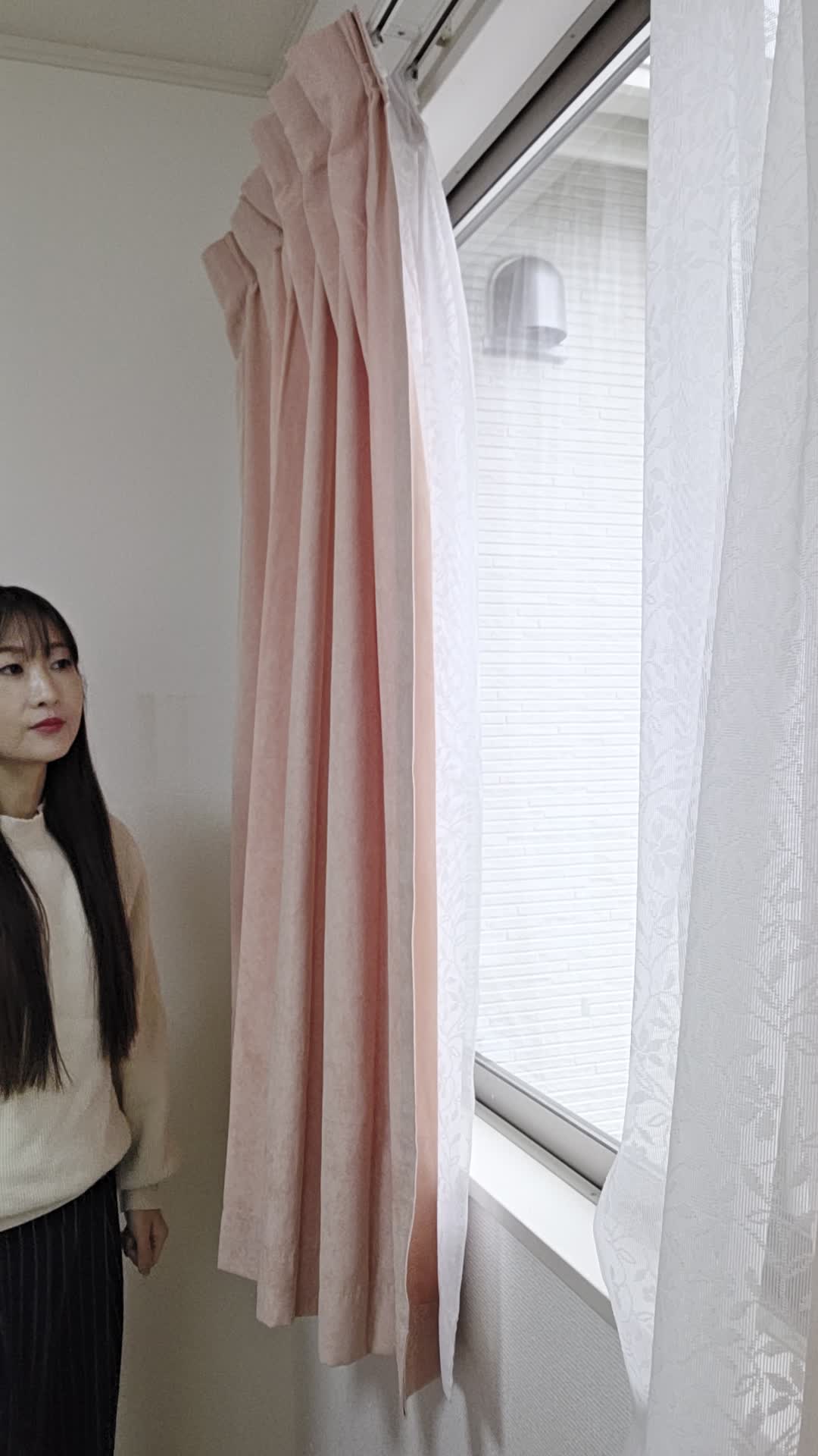 窓の方に歩いて行き、外を眺めながら軽く首を傾げる