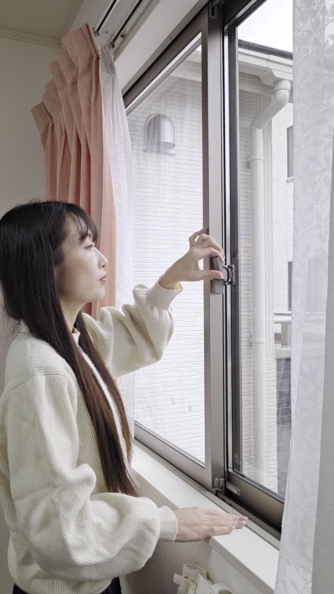 窓の鍵をゆっくり回して開閉する仕草