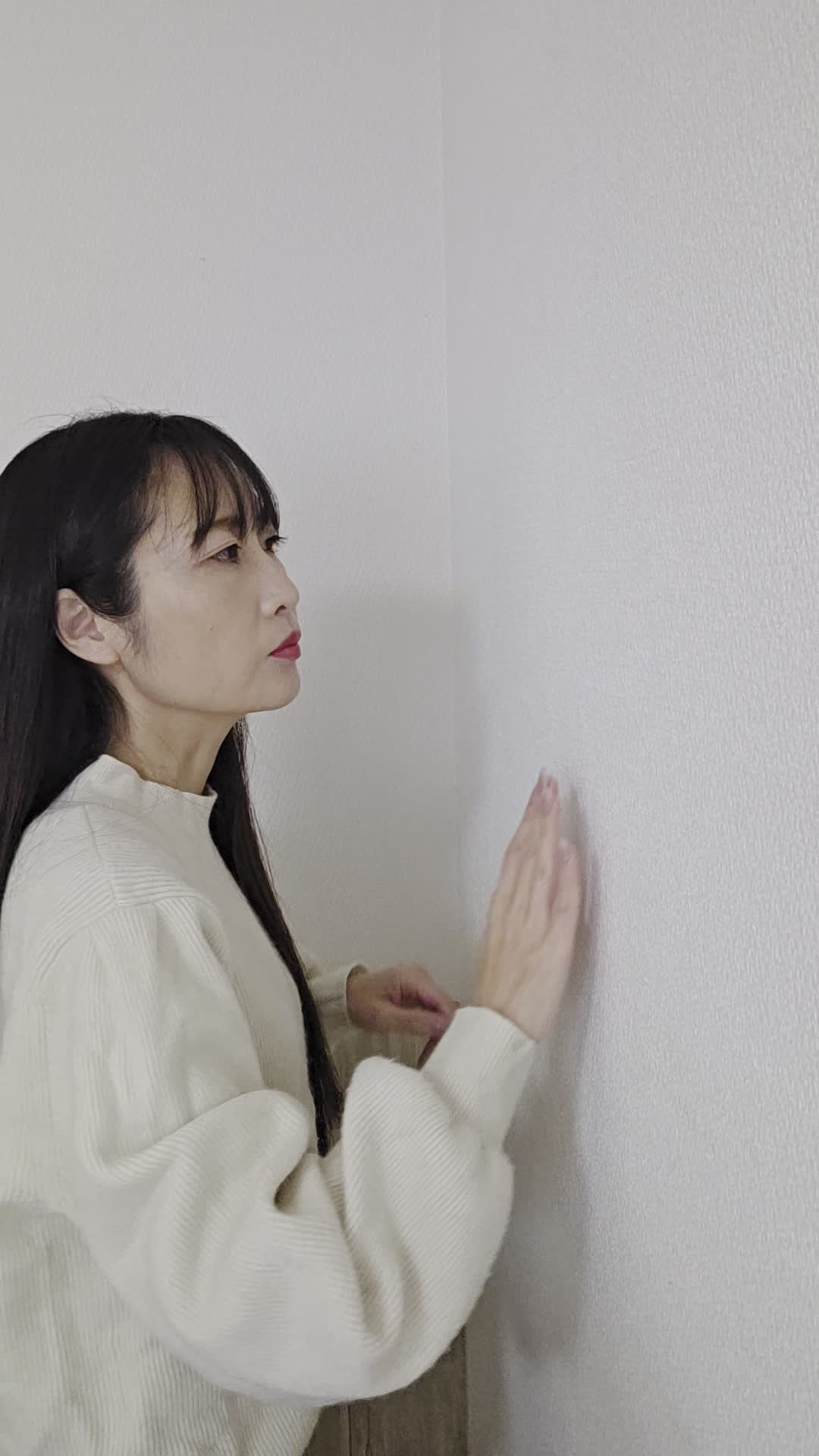 壁に耳を当てて何かを聞いているような仕草
