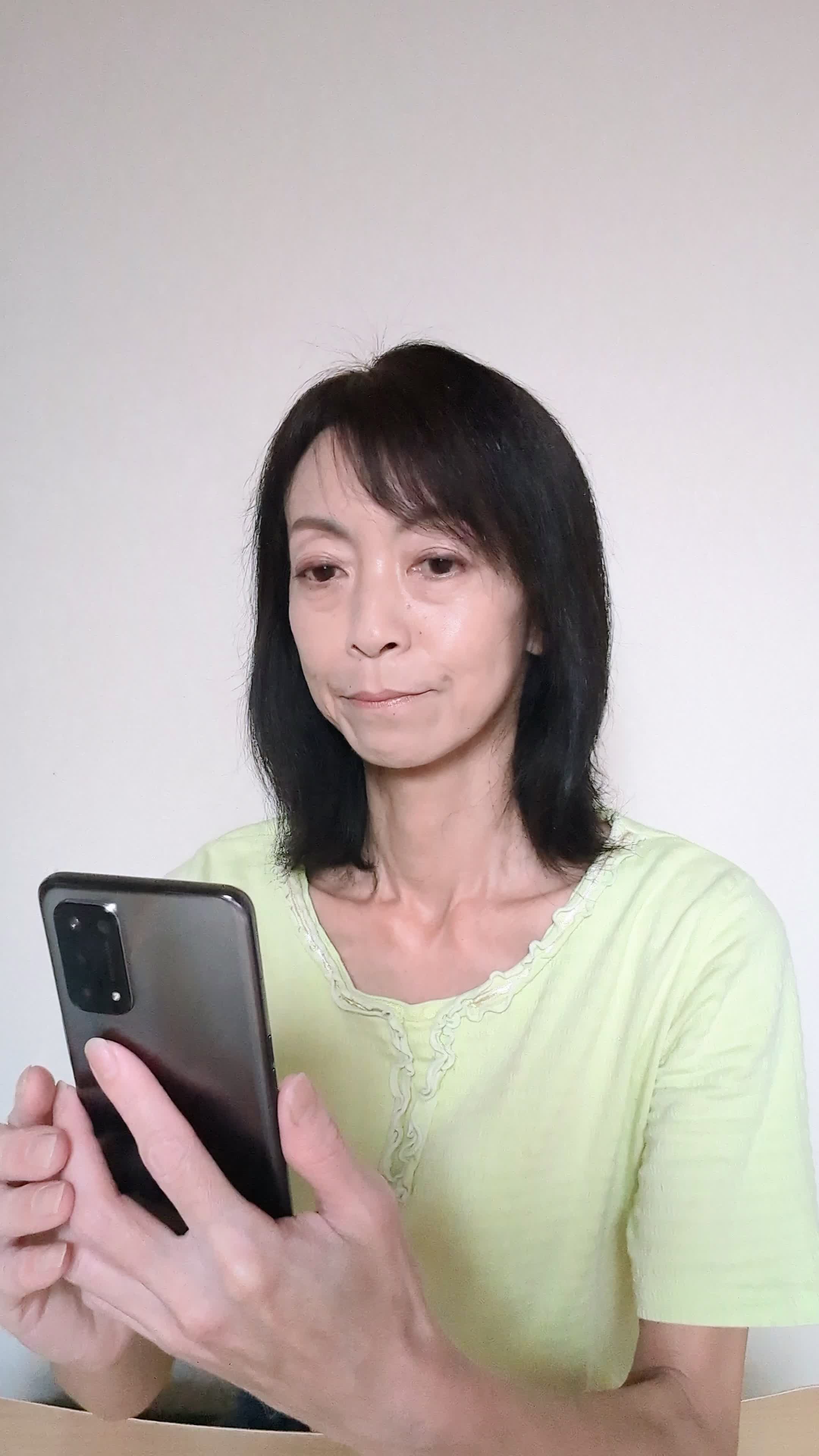 椅子に座り、スマホでカートの中身を確認しながら「これ全部買おうかな？」と悩む表情