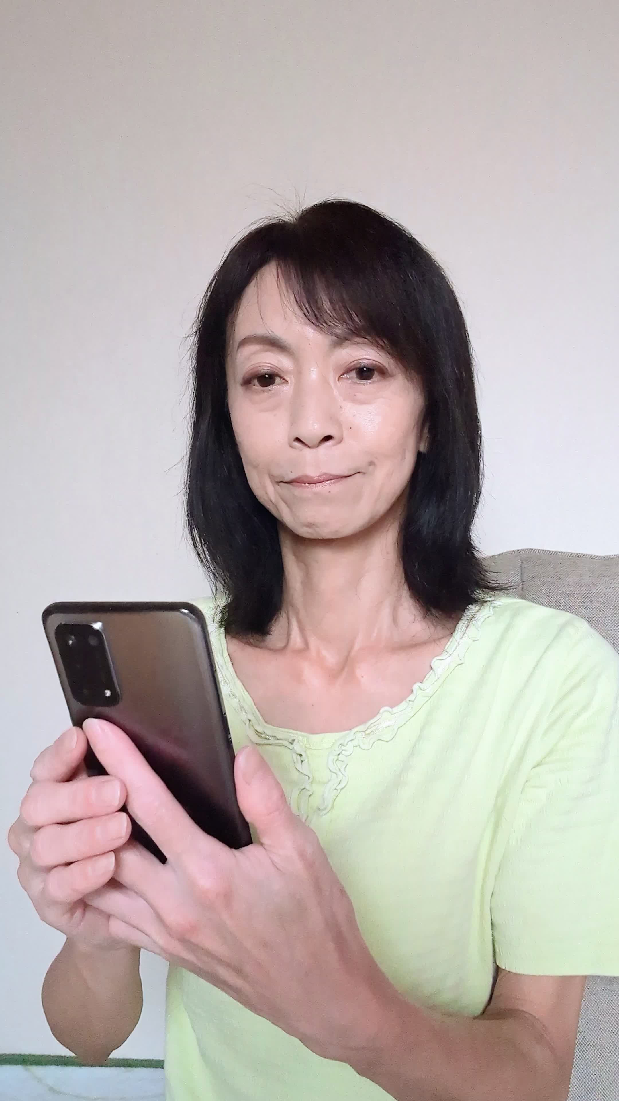 椅子に浅く腰掛け、「クーポンを適用してさらにお得に」とスマホを操作する姿
